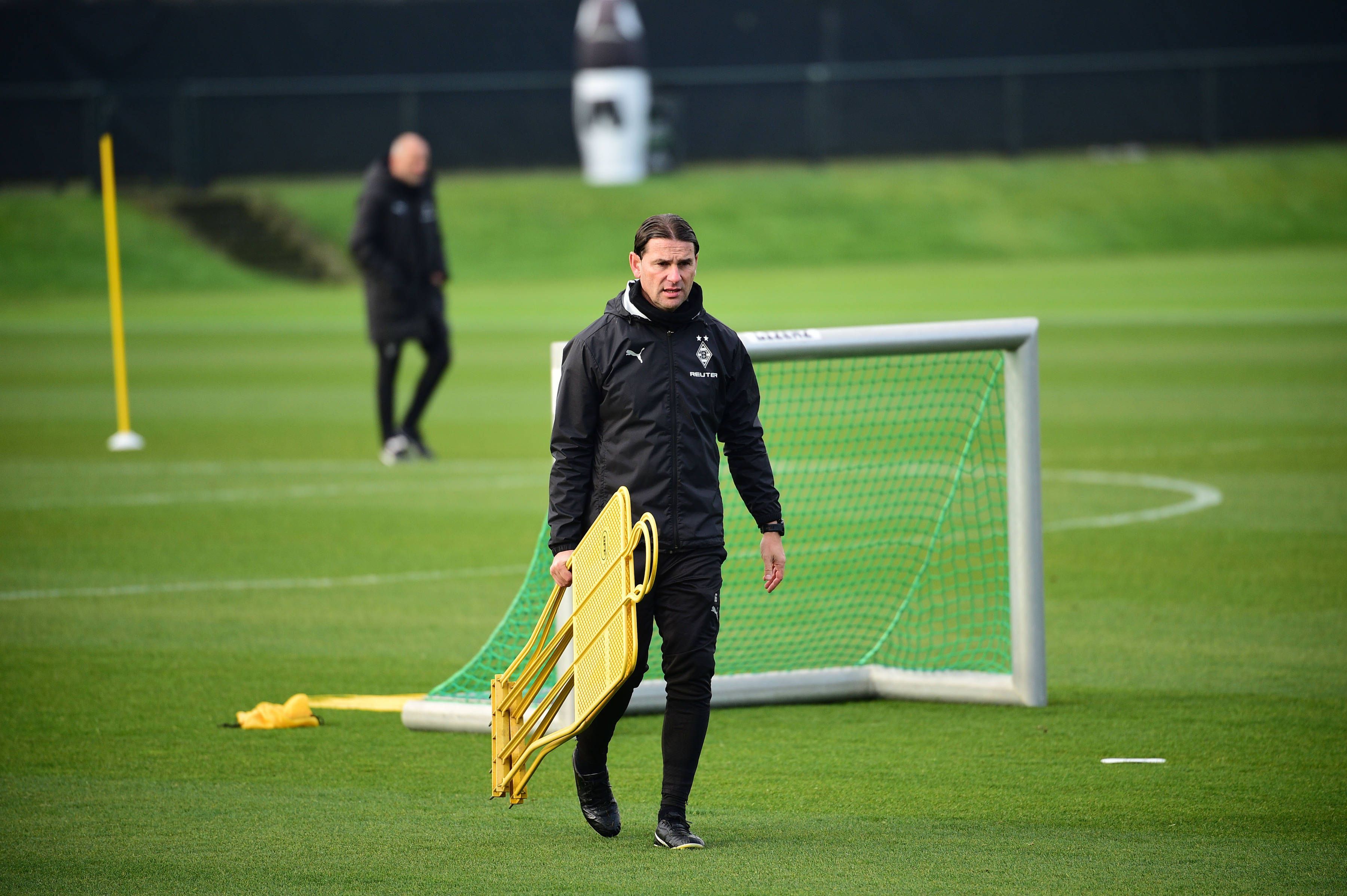 Borussia Mönchengladbachs Coach Gerardo Seoane läuft über den Trainingsplatz und trägt zwei Aufsteller in der rechten Hand.
