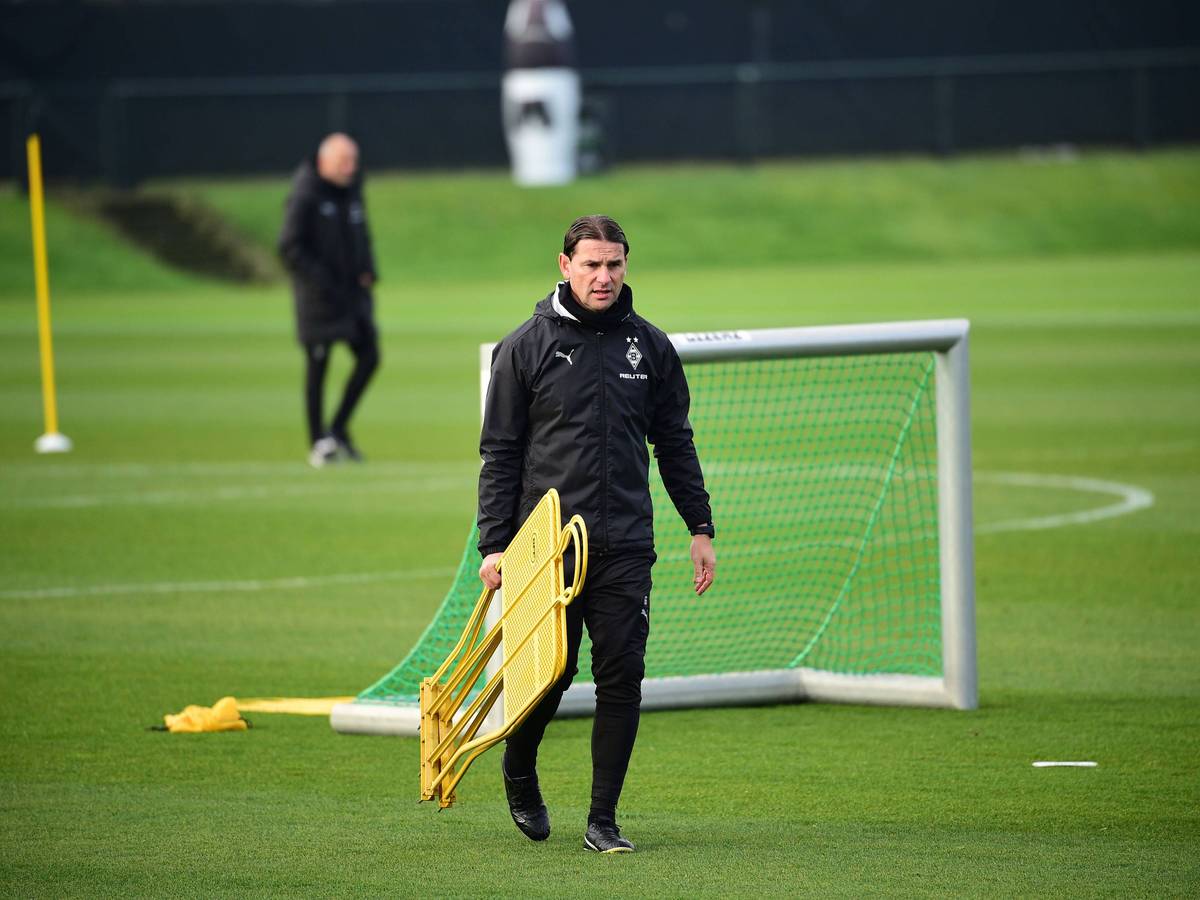 Borussia Mönchengladbachs Coach Gerardo Seoane läuft über den Trainingsplatz und trägt zwei Aufsteller in der rechten Hand.