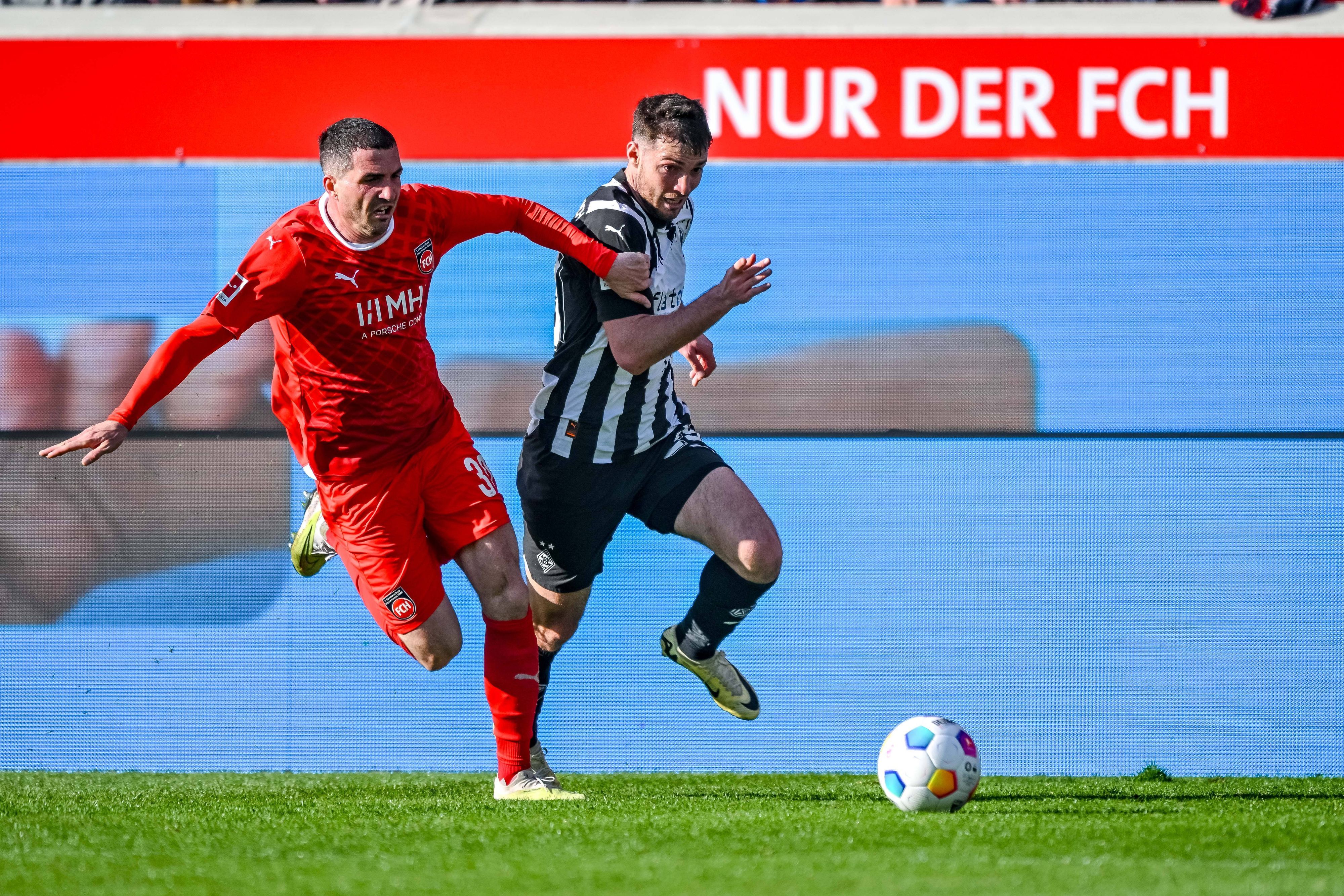 Heidenheims Norman Theuerkauf und Borussia Mönchengladbachs Joe Scally kämpfen im Laufduell um den Ball.