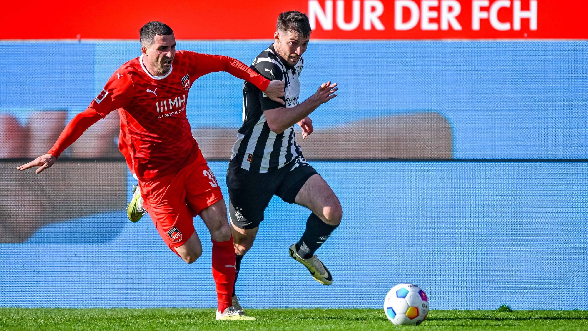 Heidenheims Norman Theuerkauf und Borussia Mönchengladbachs Joe Scally kämpfen im Laufduell um den Ball.