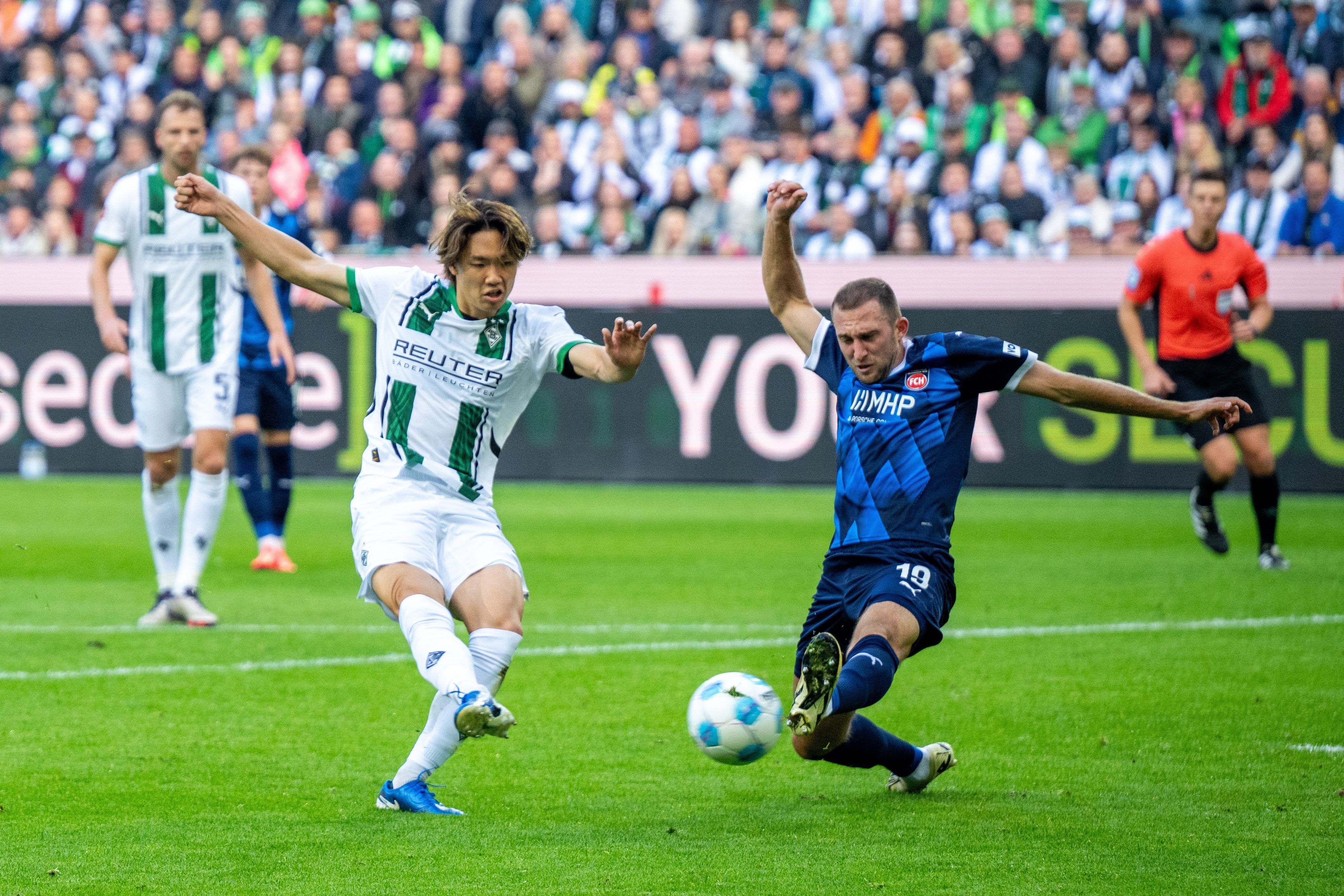 Borussia Mönchengladbachs Ko Itakura zieht ab, Heidenheims Jonas Föhrenbach versucht zu blocken.