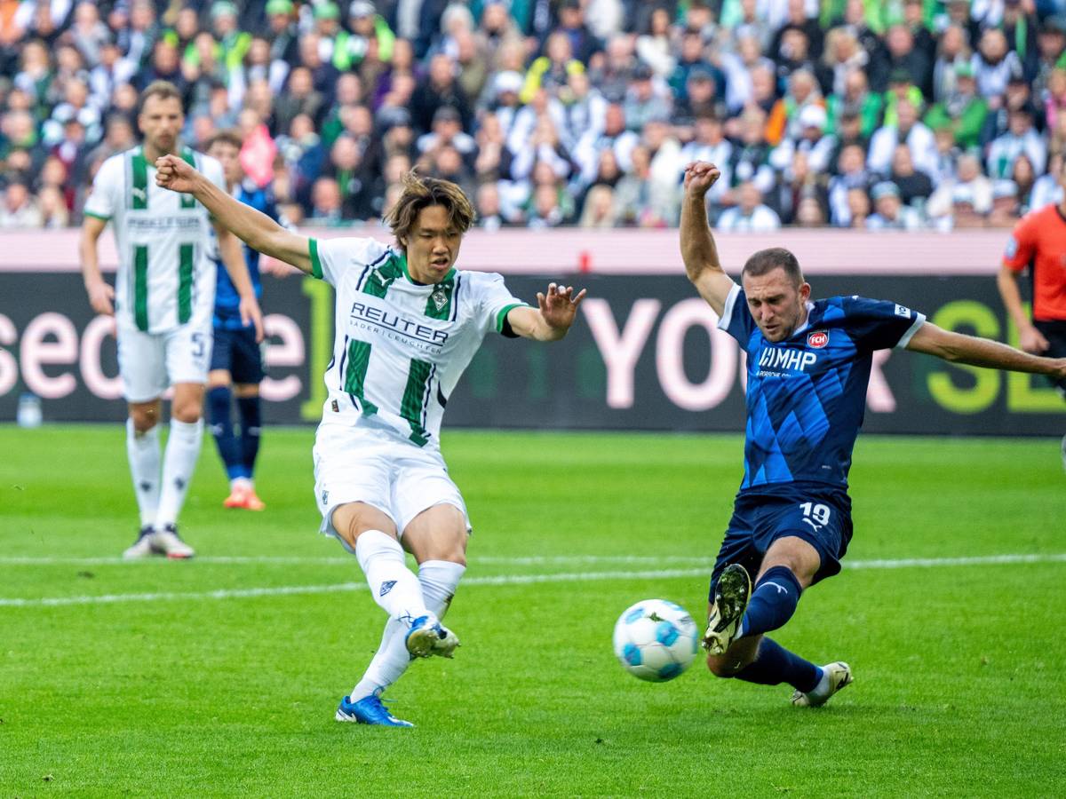 Borussia Mönchengladbachs Ko Itakura zieht ab, Heidenheims Jonas Föhrenbach versucht zu blocken.