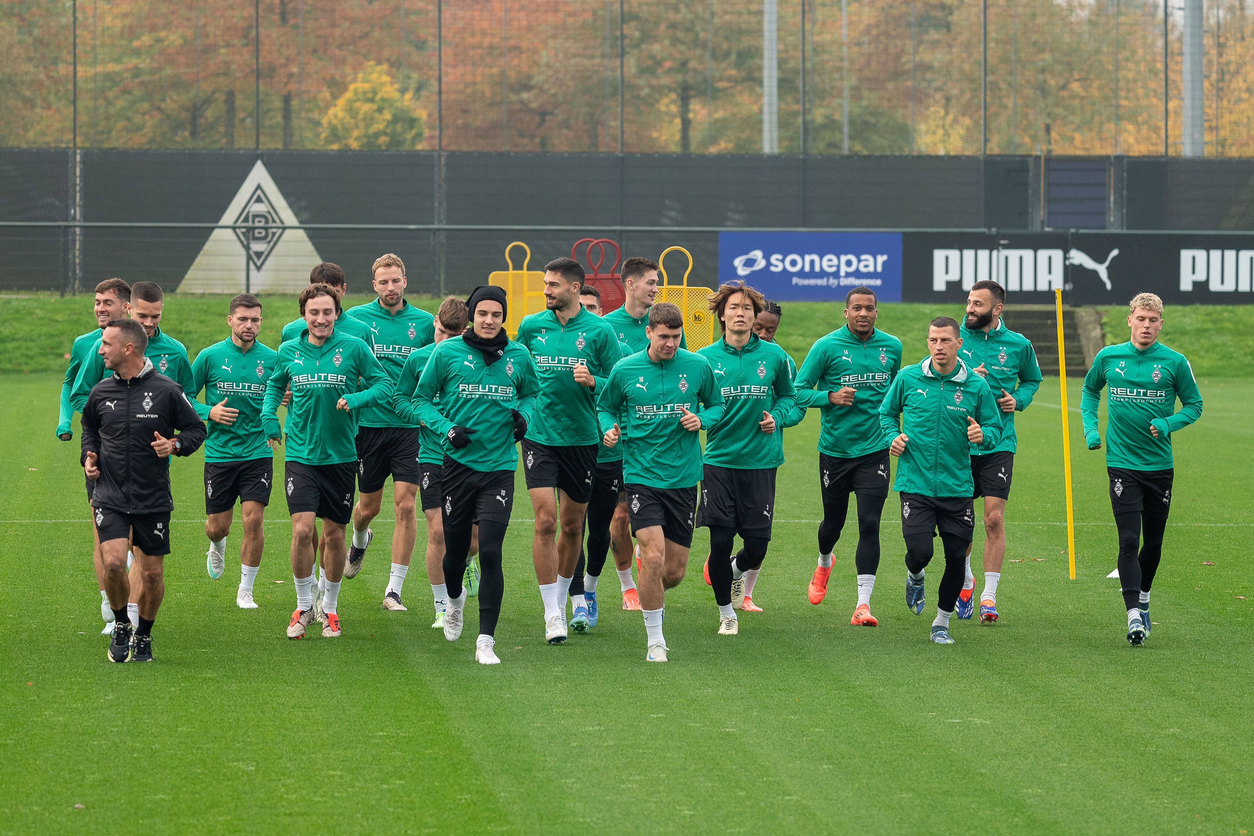 Die Spieler von Borussia Mönchengladbach laufen sich gemeinsam auf dem Trainingsplatz warm.