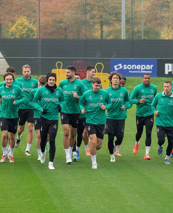 Die Spieler von Borussia Mönchengladbach laufen sich gemeinsam auf dem Trainingsplatz warm.
