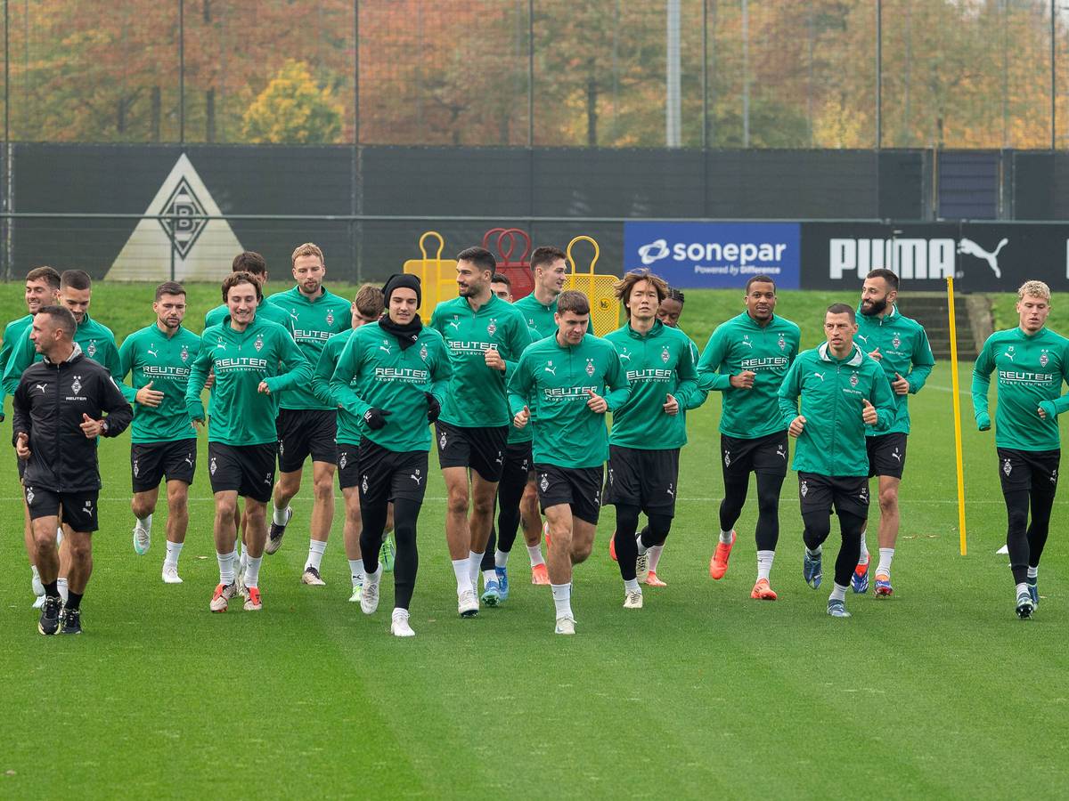 Die Spieler von Borussia Mönchengladbach laufen sich gemeinsam auf dem Trainingsplatz warm.