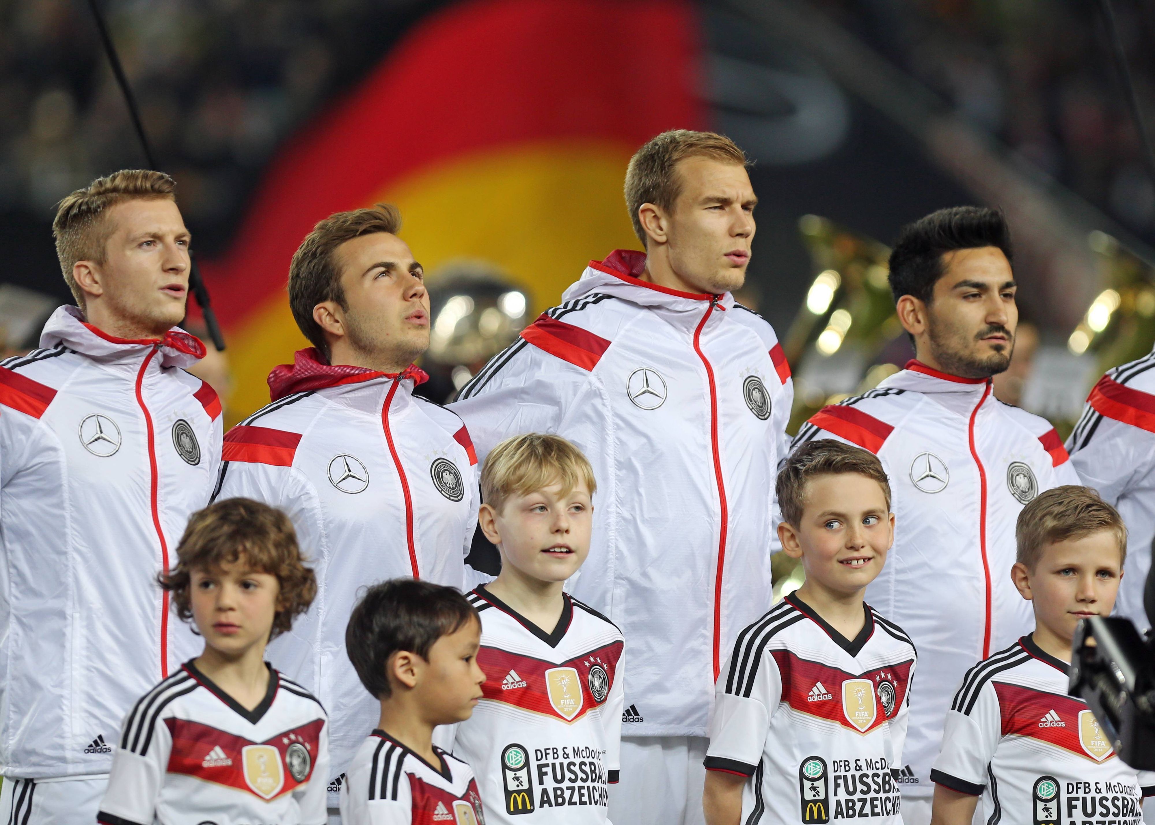 Die DFB-Elf bei der Nationalhymne in weißen Sportjacken.