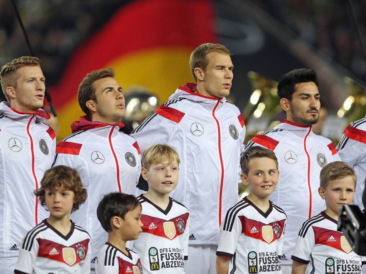 Die DFB-Elf bei der Nationalhymne in weißen Sportjacken.