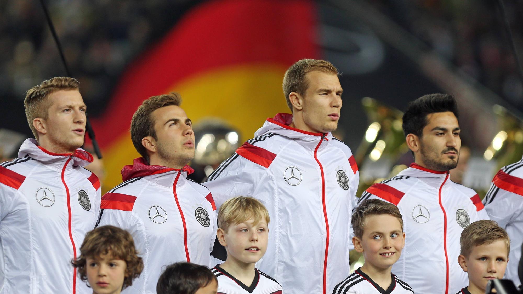Die DFB-Elf bei der Nationalhymne in weißen Sportjacken.