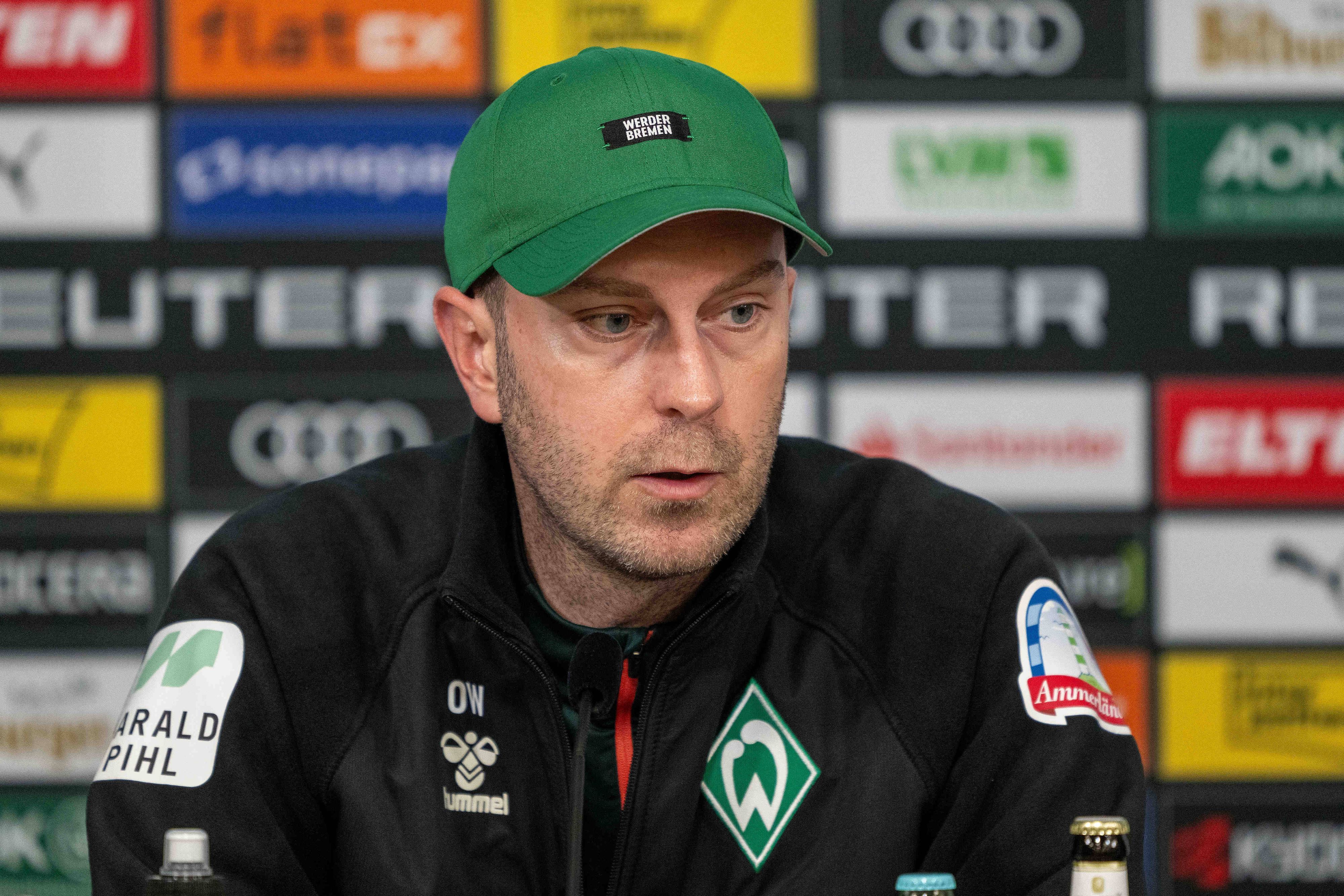 Werder Bremens Trainer Ole Werner sitzt auf dem Podium und spricht bei der Pressekonferenz.