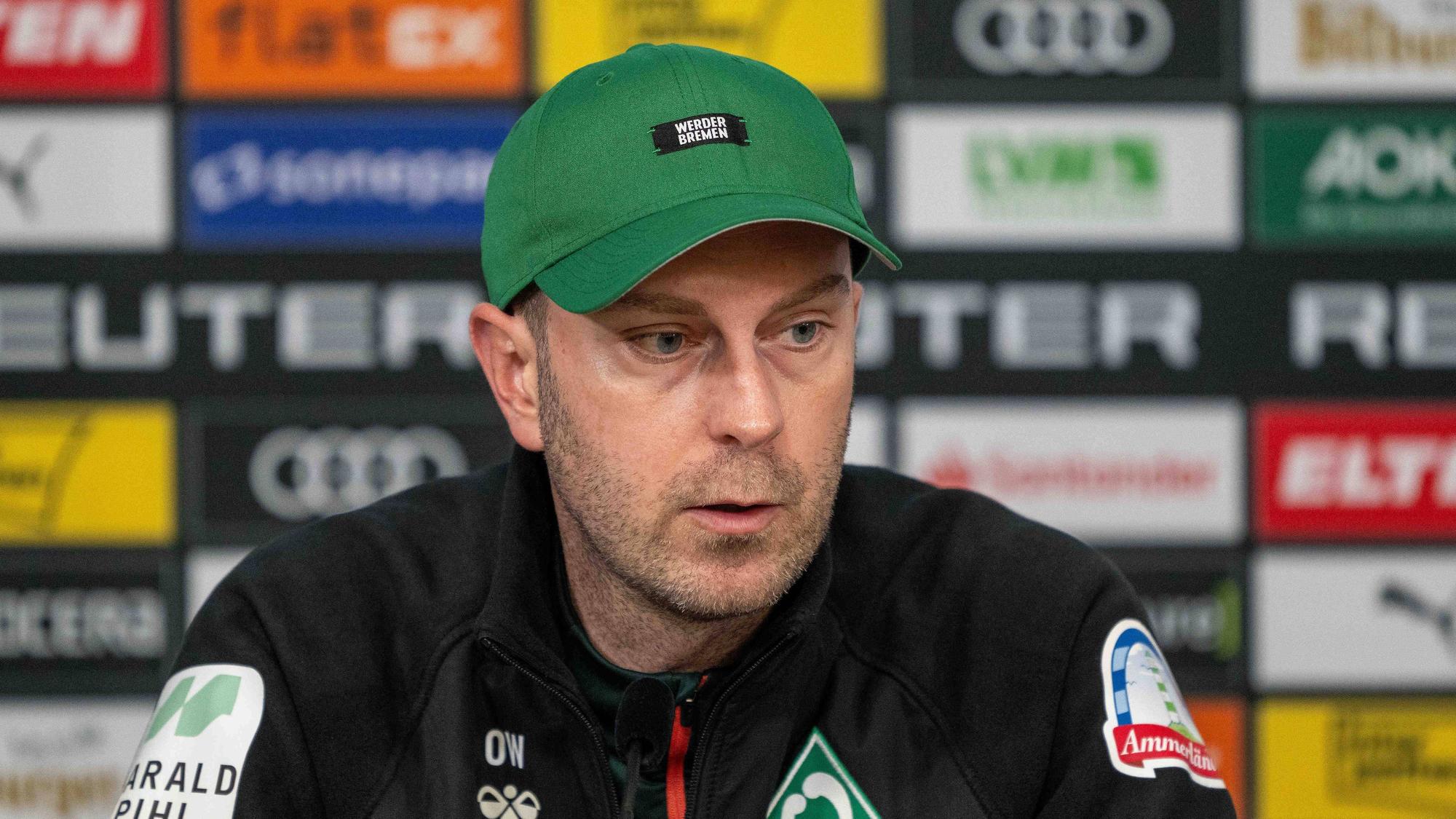 Werder Bremens Trainer Ole Werner sitzt auf dem Podium und spricht bei der Pressekonferenz.