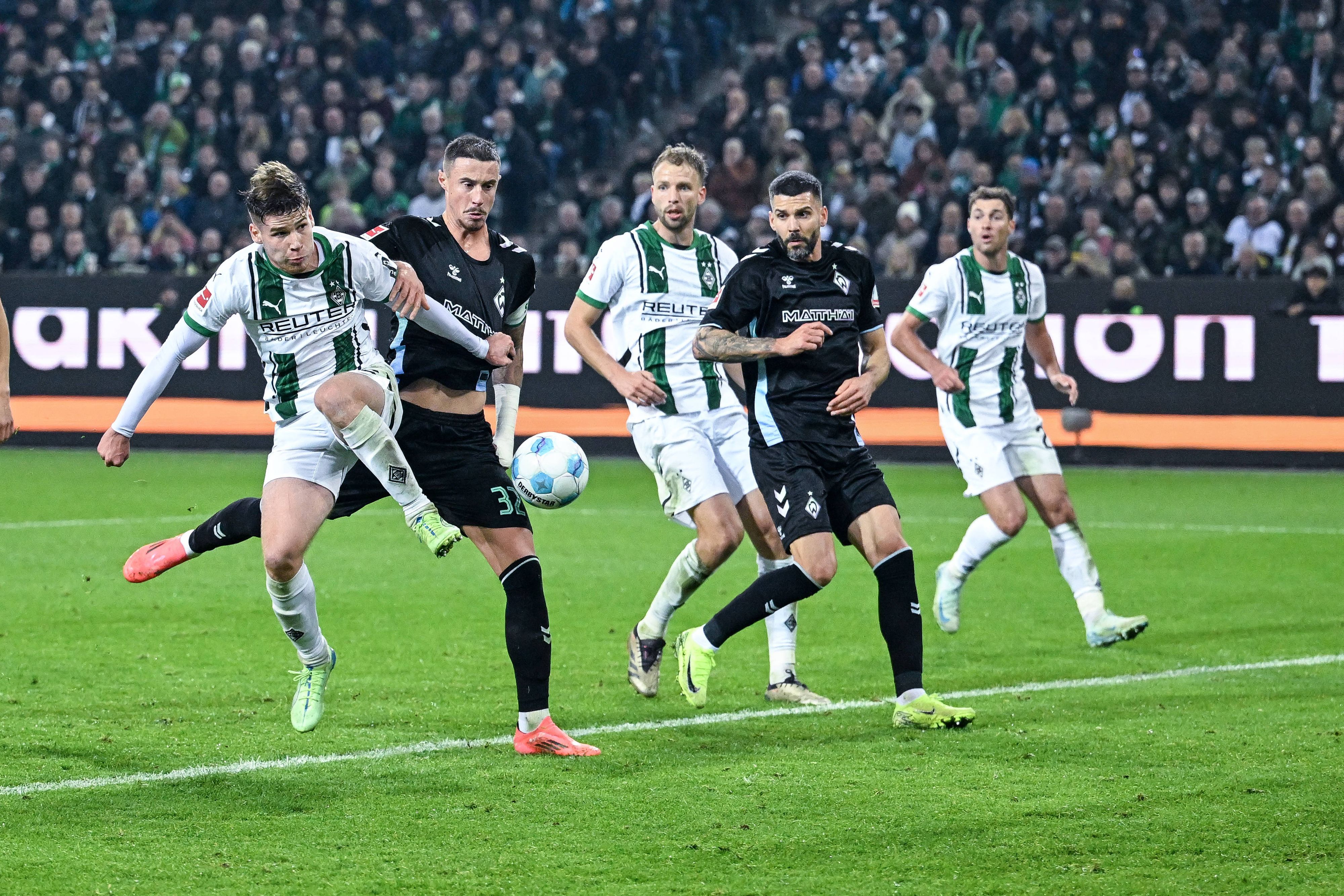 Die Gladbach-Profis Lukas Ullrich, Marvin Friedrich und Joe Scally gehen im Spiel gegen Werder Bremen zum Ball.