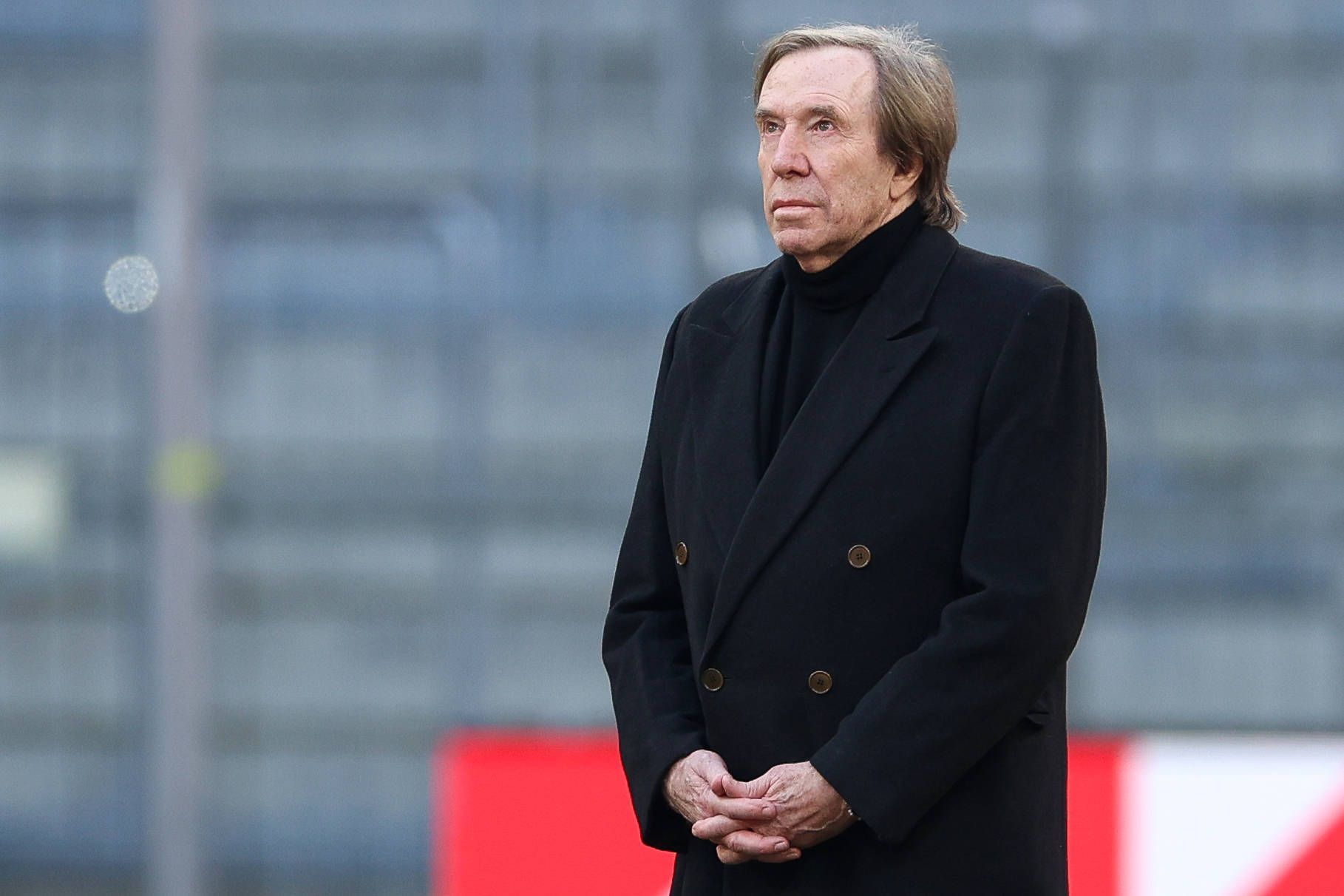 Günter Netzer im schwarzen Mantel in der Allianz-Arena.