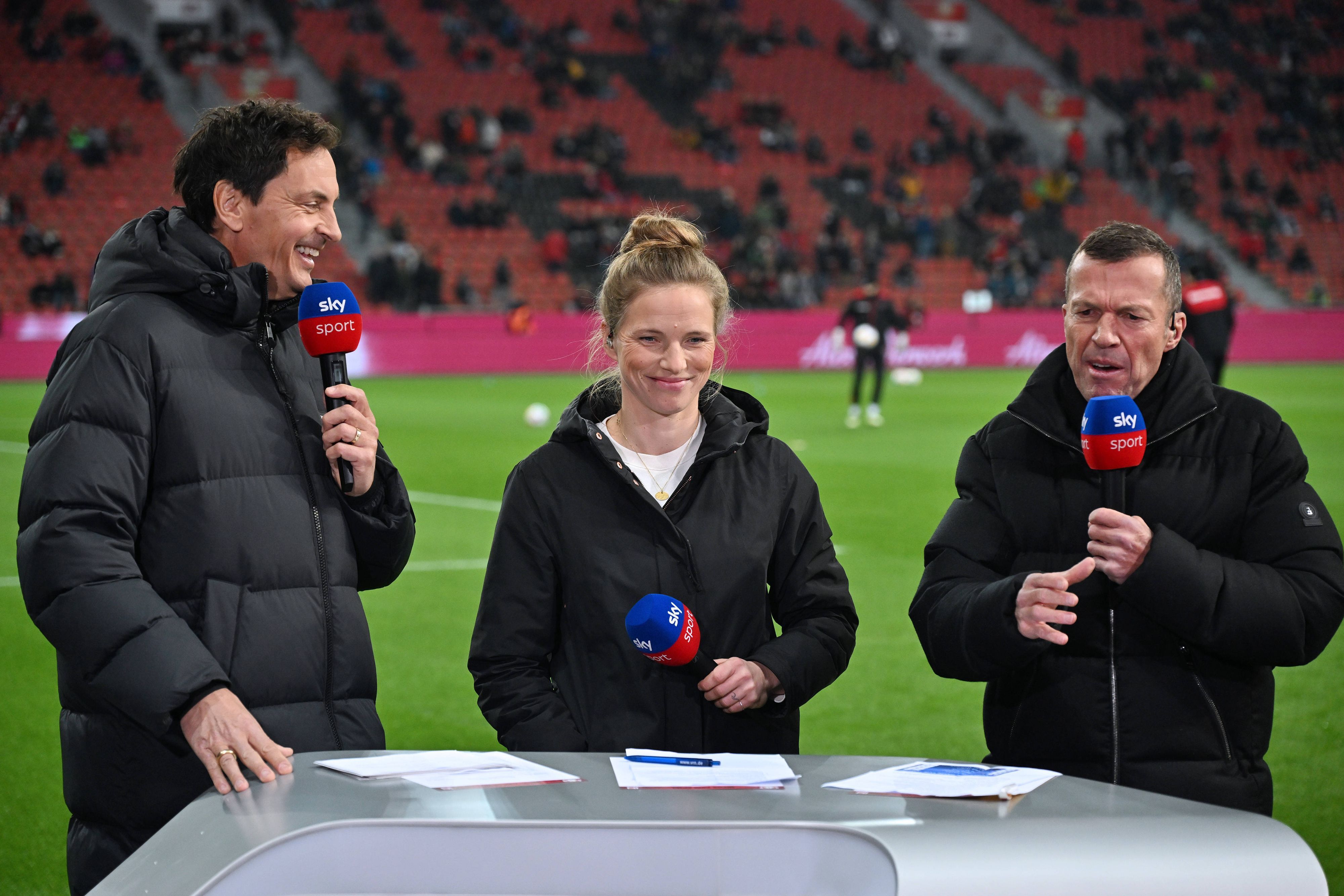 Sky-Moderator Sebastian Hellmann und die Experten Tabea Kemme sowie Lothar Matthäus stehen gemeinsam in Leverkusen am Pult.