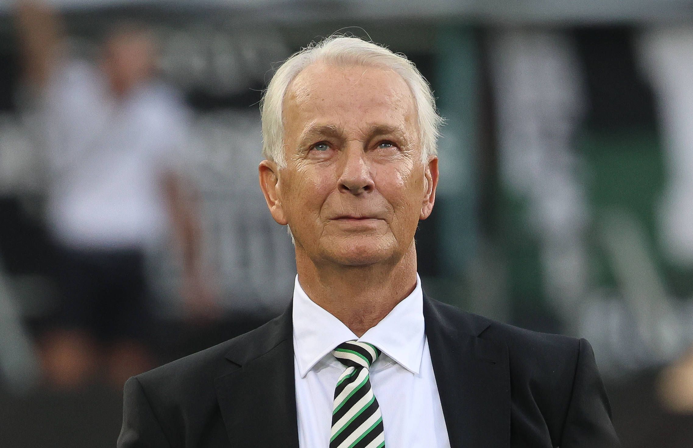 Borussia Mönchengladbachs Präsident Rainer Bonhof steht beim Bundesliga-Spiel gegen Bayer leverkusen in der Arena und blickt auf die Tribüne.