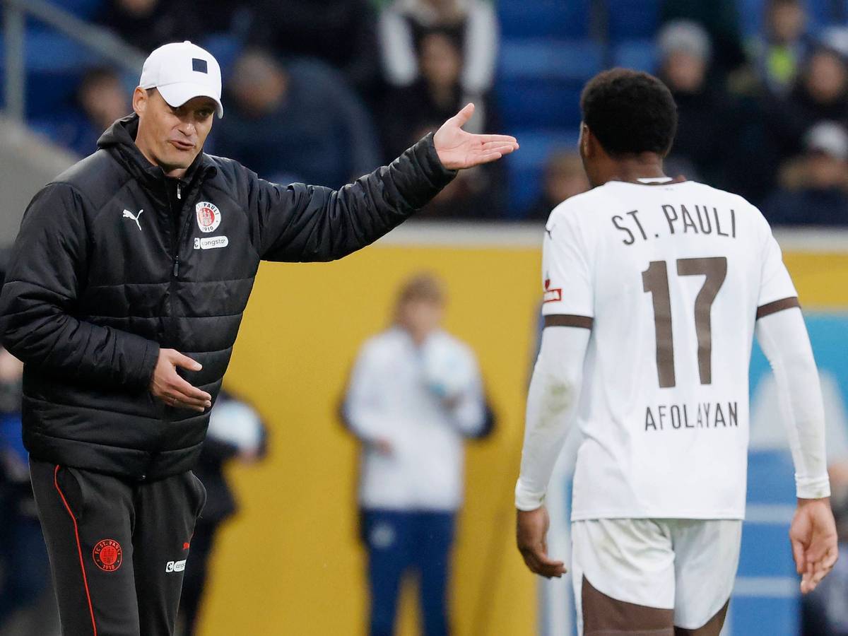 St. Paulis Trainer Alexander Blessin gibt seinem Stürmer Oladapo Afolayan im Spiel bei der TSG Hoffenheim an der Seitenlinie Anweisungen.