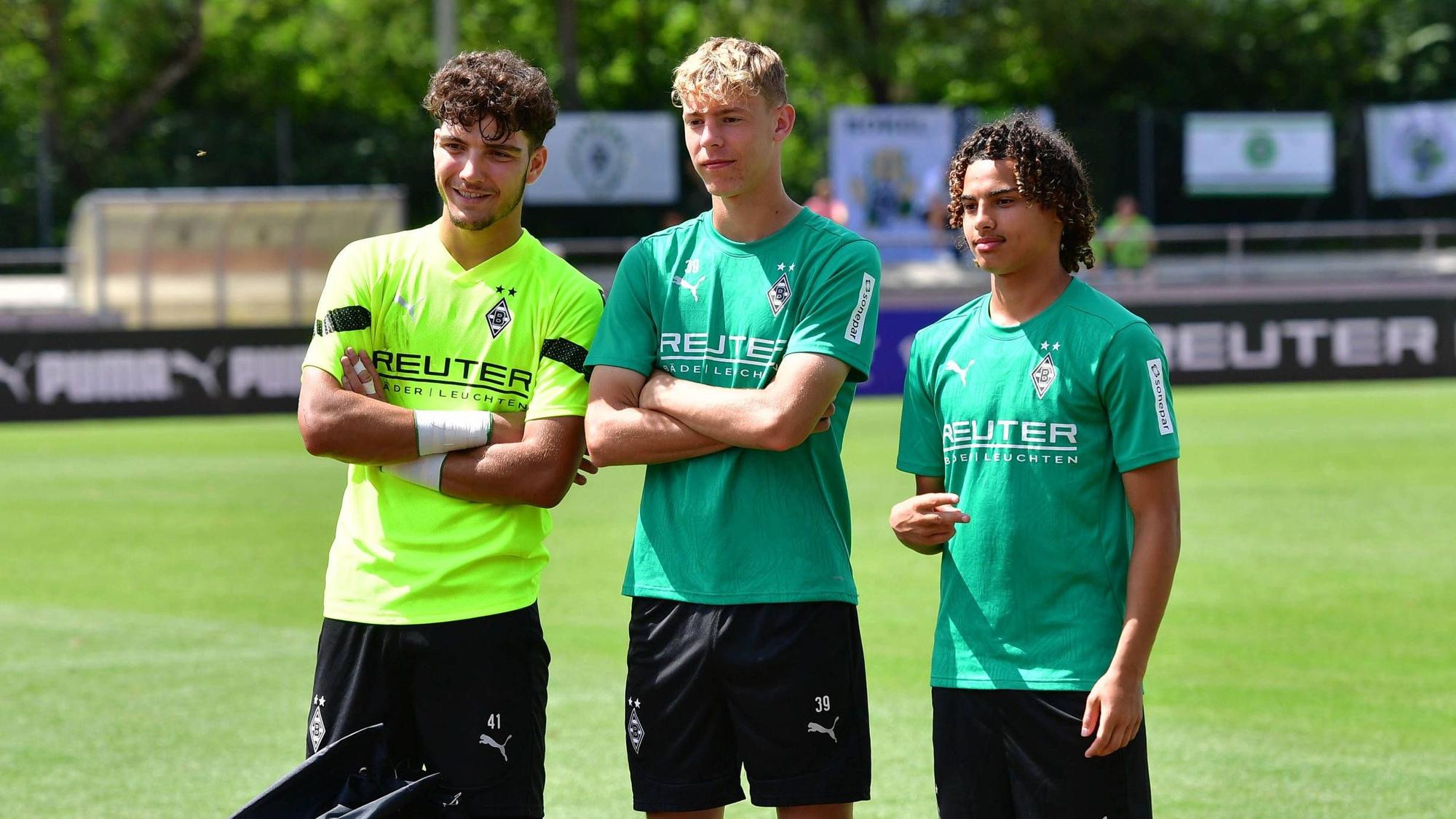 Borussia Mönchengladbachs U19-Spieler Tiago Pereira Cardoso, Niklas Swider und Kilian Sauck stehen nebeneinander auf dem Trainingsplatz und posieren für ein Foto.