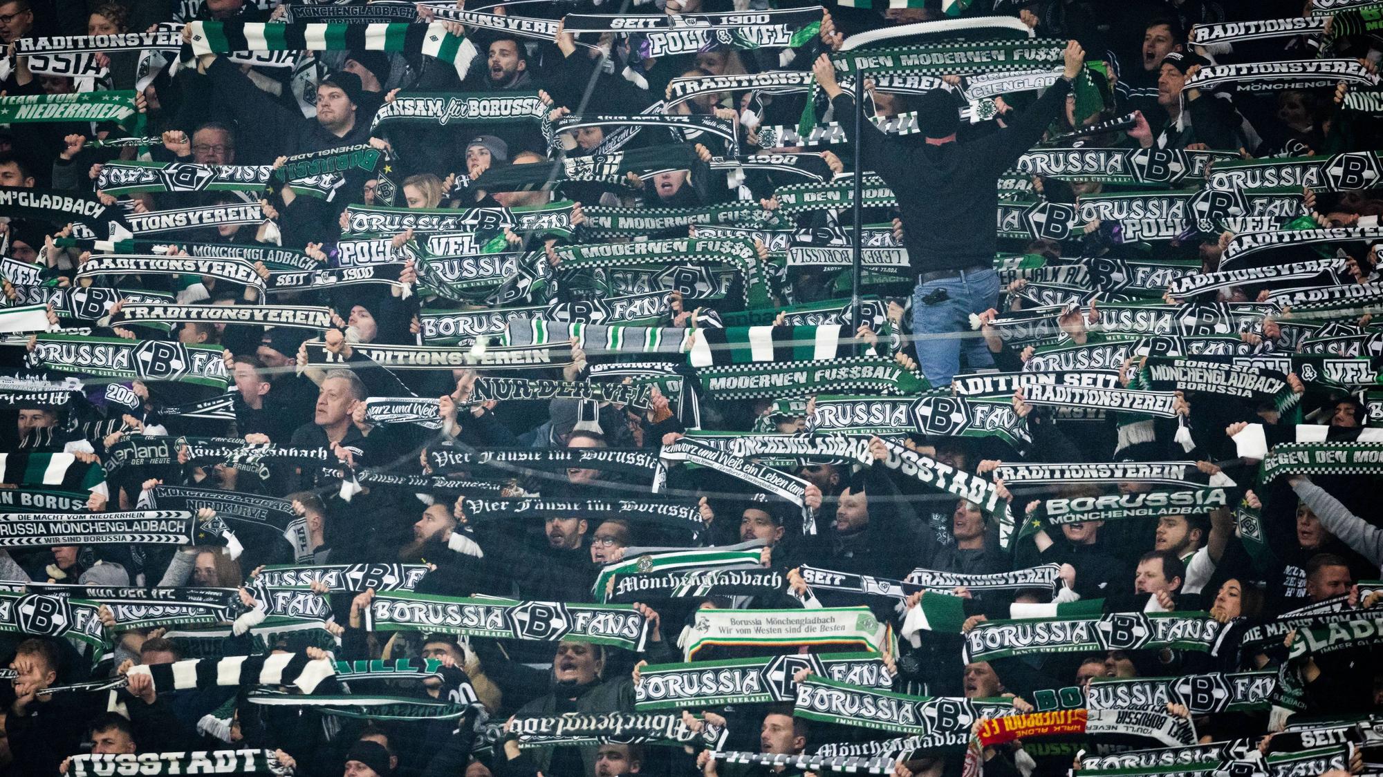 Fans von Borussia Mönchengladbach halten beim Auswärtsspiel gegen RB Leipzig ihre Schals in die Höhe.
