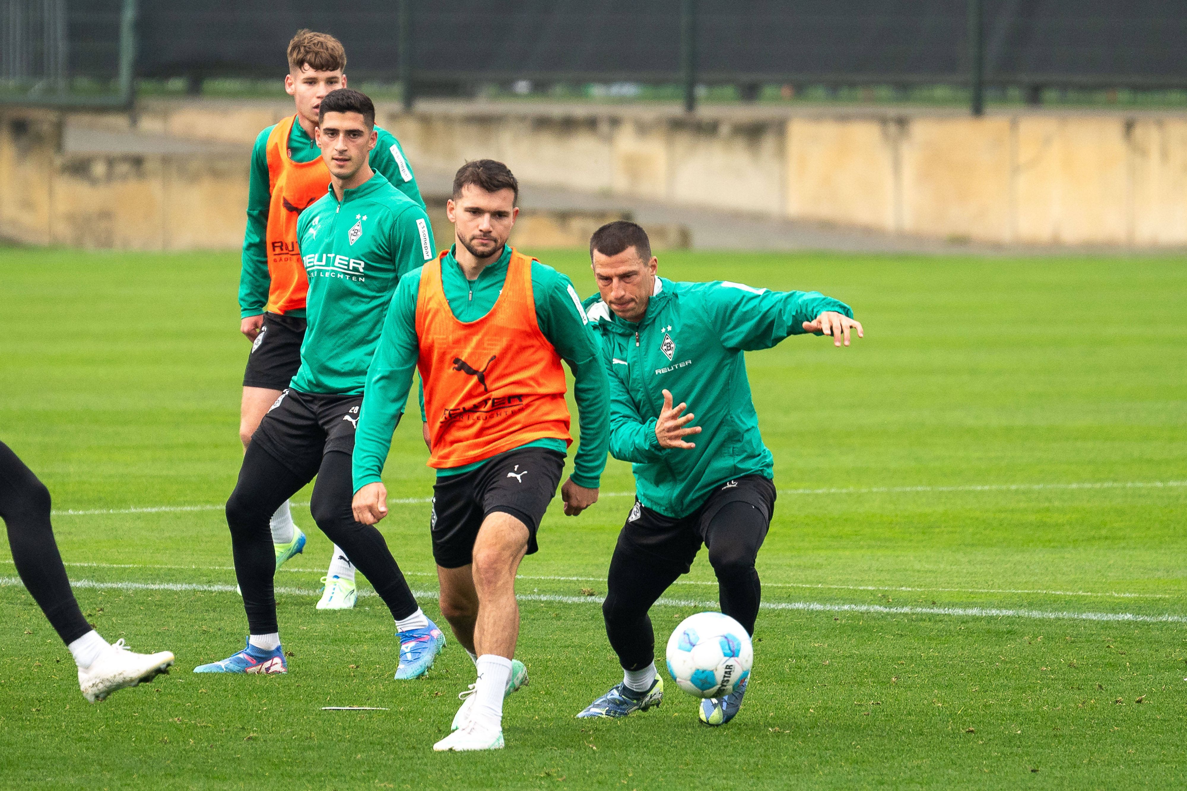 Borussia Mönchengladbachs Kevin Stöger und Teamkollege Stefan Lainer kämpfen im Training um den Ball. Im Hintergrund beobachten Grant-Leon Ranos und Lukas Ullrich die Szene.