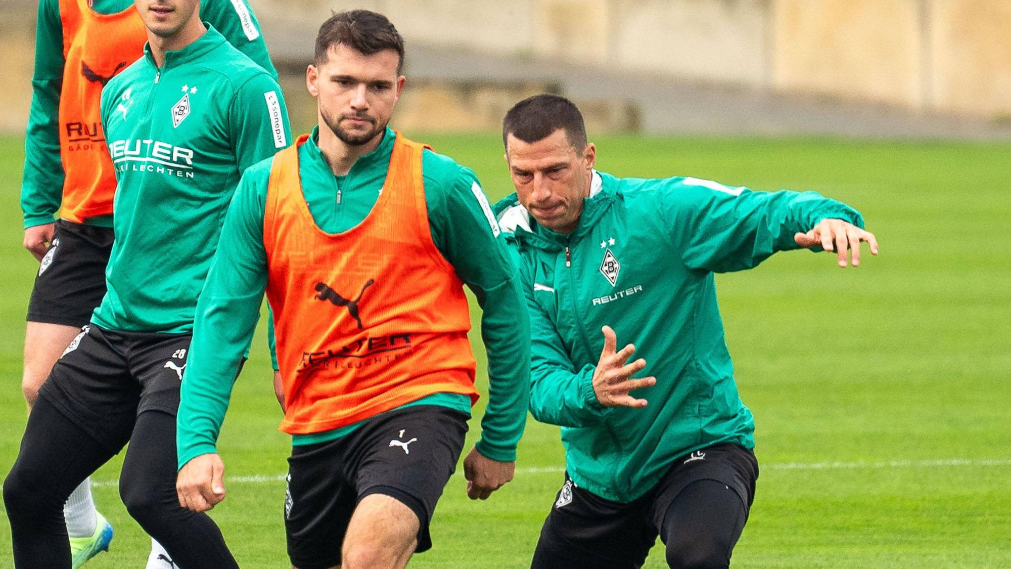 Borussia Mönchengladbachs Kevin Stöger und Teamkollege Stefan Lainer kämpfen im Training um den Ball. Im Hintergrund beobachten Grant-Leon Ranos und Lukas Ullrich die Szene.