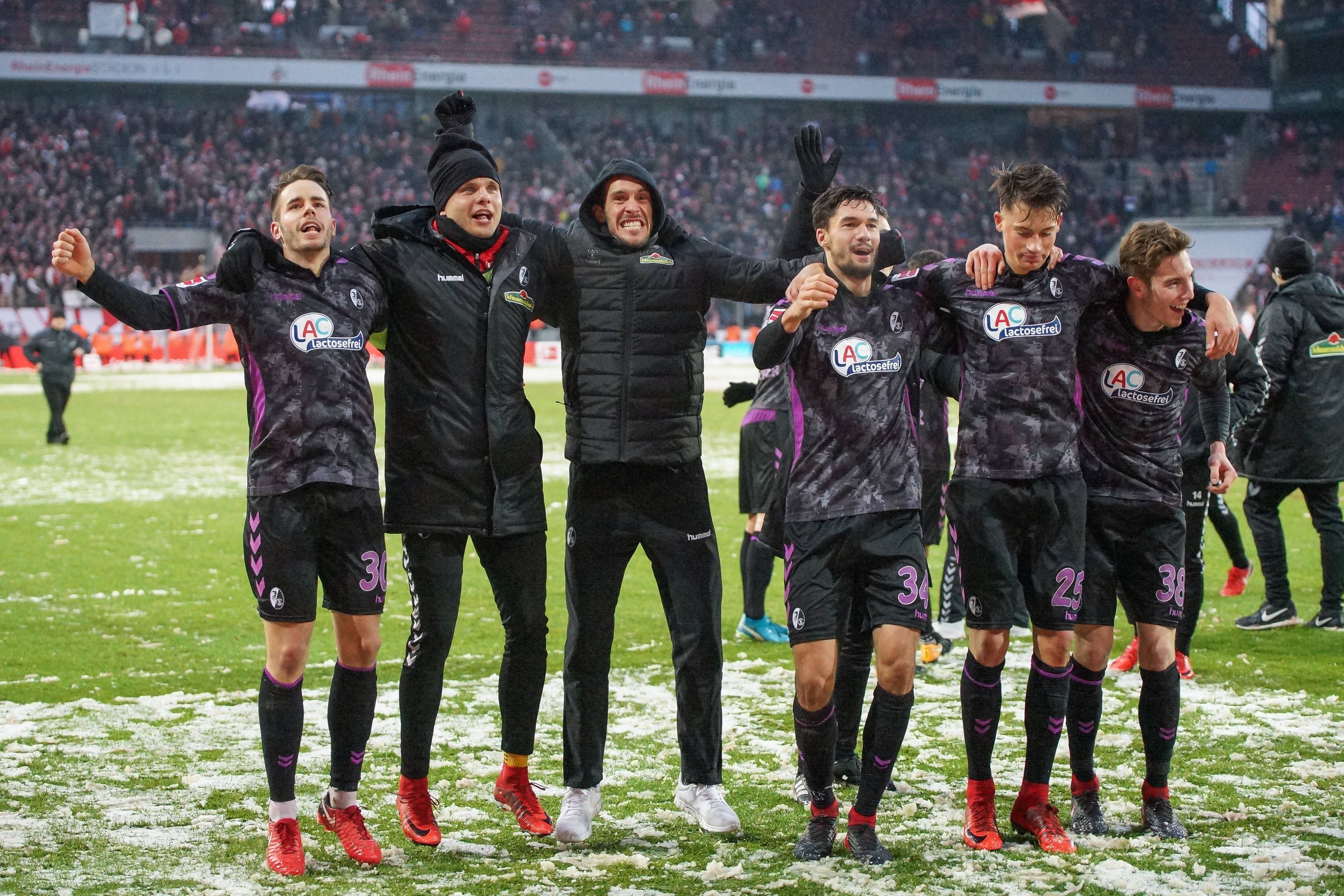 Die Freiburger Profis Rafal Gikiewicz, Julian Schuster, Tim Kleindienst und Robin Koch feiern mit den Fans vor der Kurve nach dem Spiel beim 1. FC Köln.