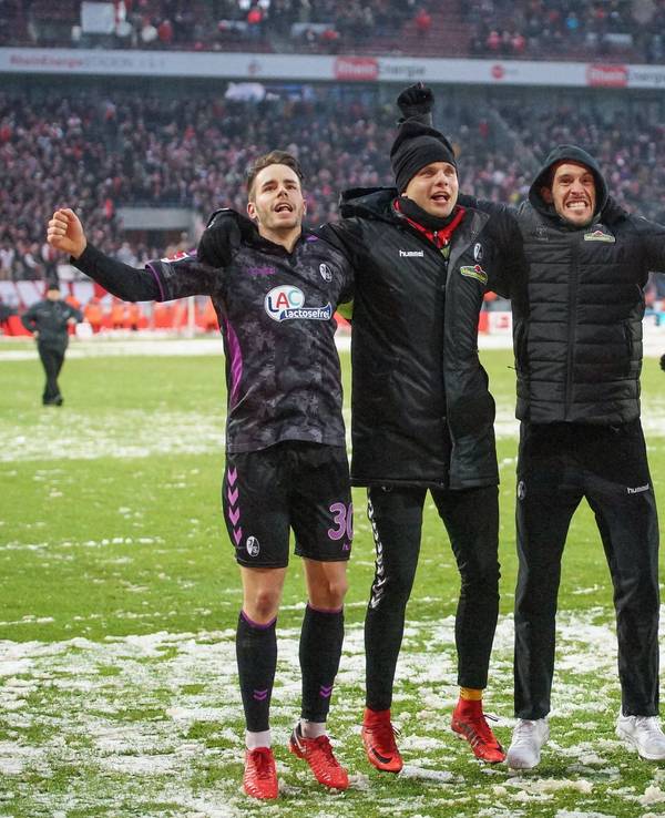 Die Freiburger Profis Rafal Gikiewicz, Julian Schuster, Tim Kleindienst und Robin Koch feiern mit den Fans vor der Kurve nach dem Spiel beim 1. FC Köln.