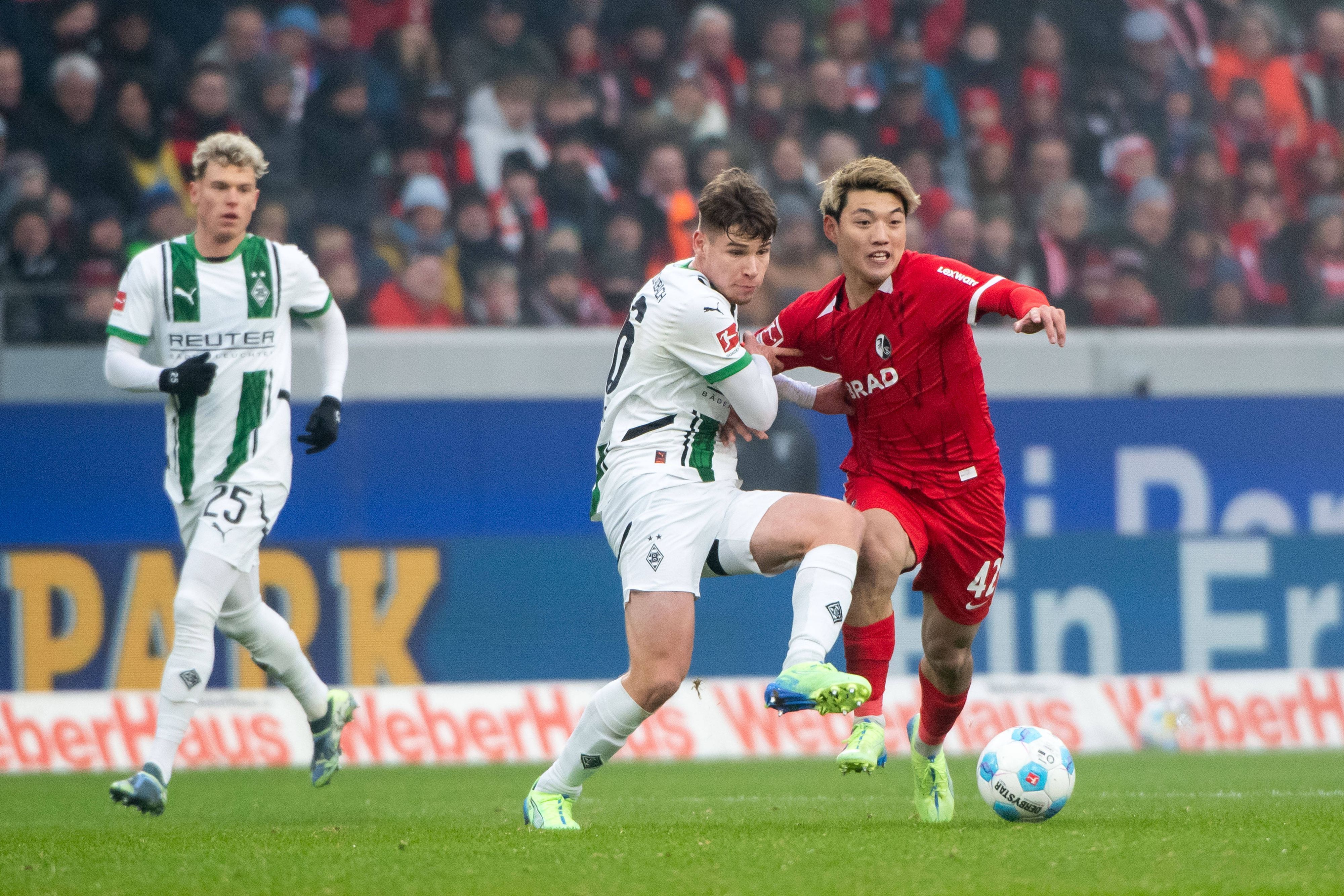 Borussia Mönchengladbachs Lukas Ullrich kämpft mit Freiburgs Ritsu Doan um den Ball.