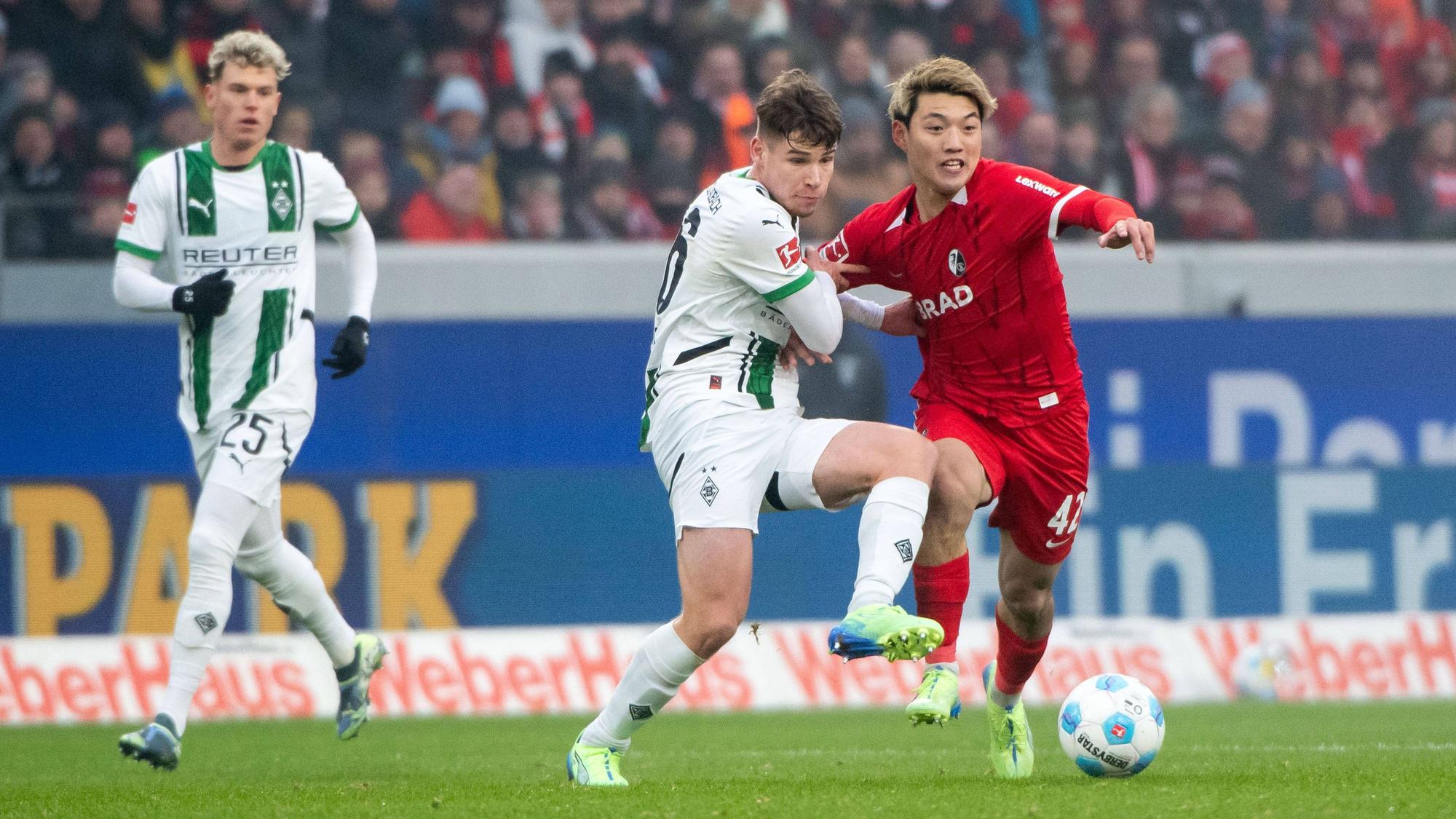 Borussia Mönchengladbachs Lukas Ullrich kämpft mit Freiburgs Ritsu Doan um den Ball.