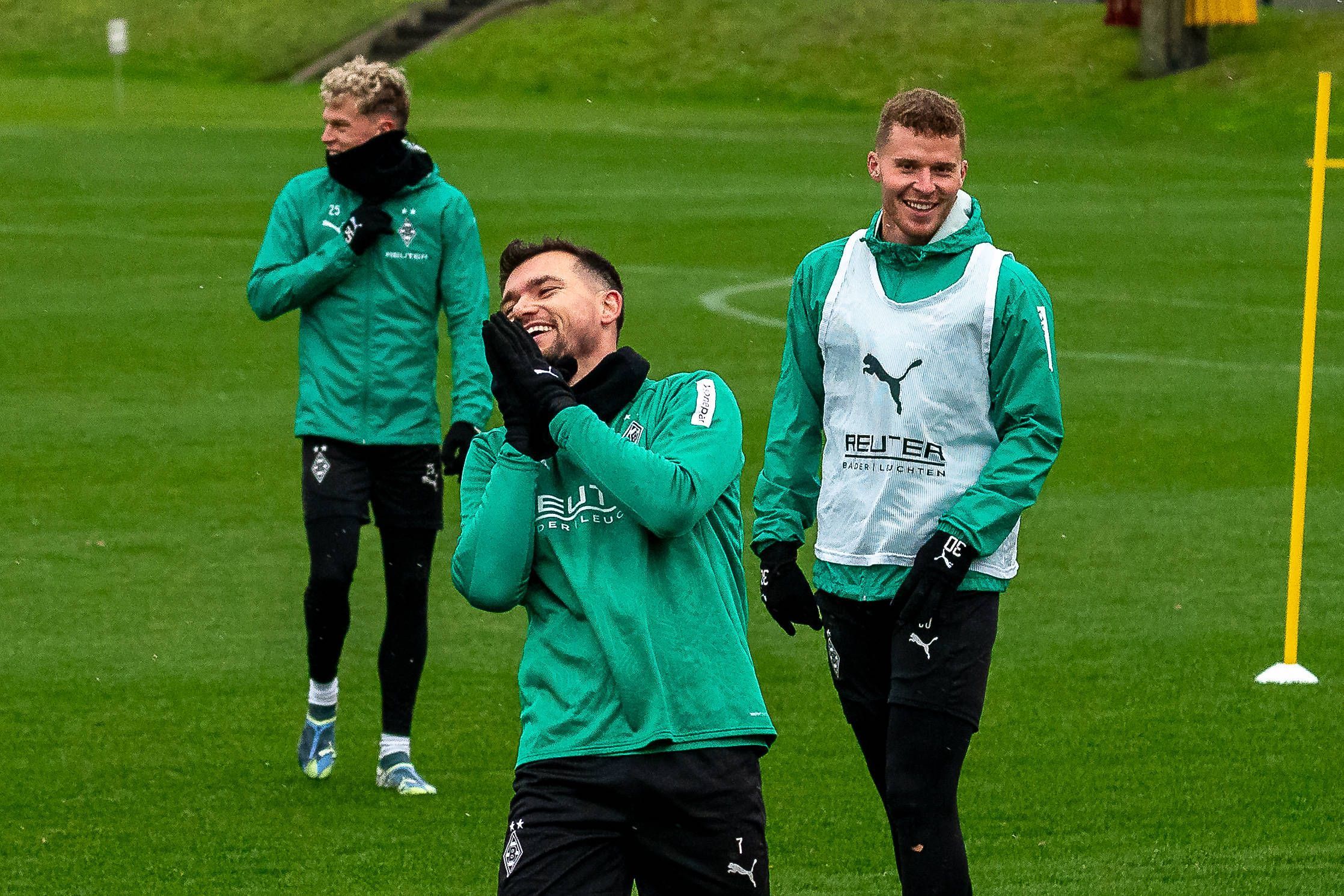 Borussia Mönchengladbachs Kevin Stöger steht lachend auf dem Trainingsplatz, dahinter steht Teamkollege Nico Elvedi und lächelt ebenfalls.