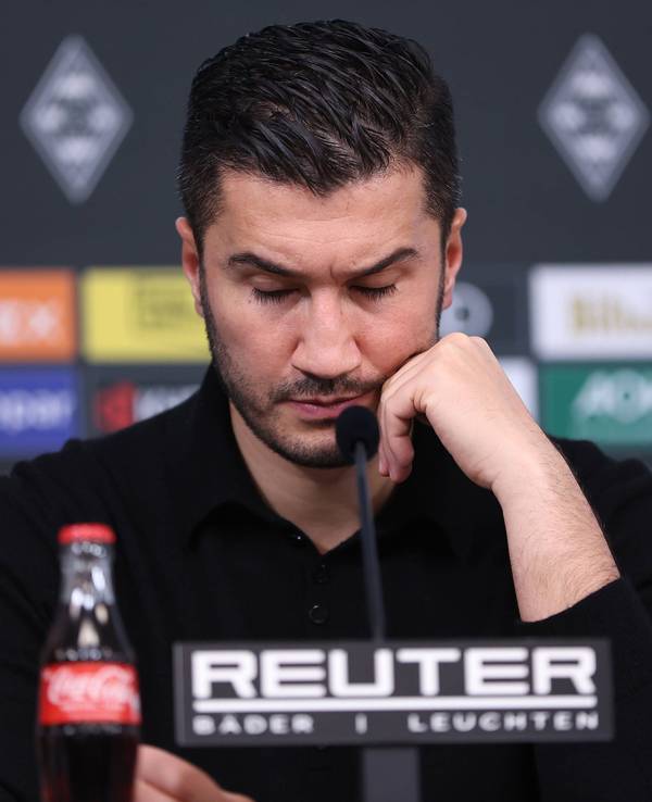 Borussia Dortmunds Trainer Nuri Sahin sitzt bei der Pressekonferenz nach dem Spiel bei Borussia Mönchengladbach auf dem Podium und stützt den Kopf auf seine linke Hand.