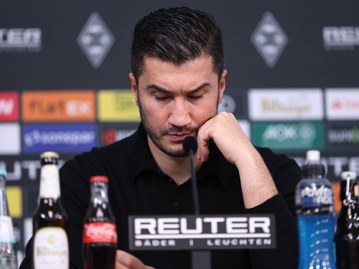 Borussia Dortmunds Trainer Nuri Sahin sitzt bei der Pressekonferenz nach dem Spiel bei Borussia Mönchengladbach auf dem Podium und stützt den Kopf auf seine linke Hand.