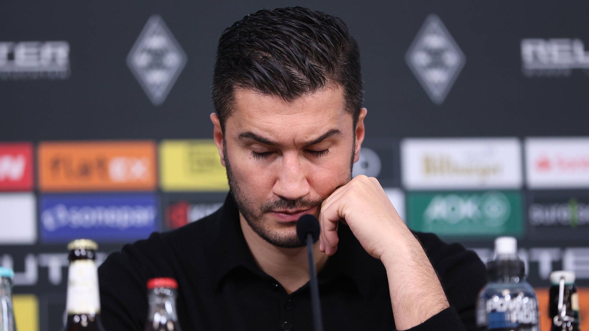 Borussia Dortmunds Trainer Nuri Sahin sitzt bei der Pressekonferenz nach dem Spiel bei Borussia Mönchengladbach auf dem Podium und stützt den Kopf auf seine linke Hand.