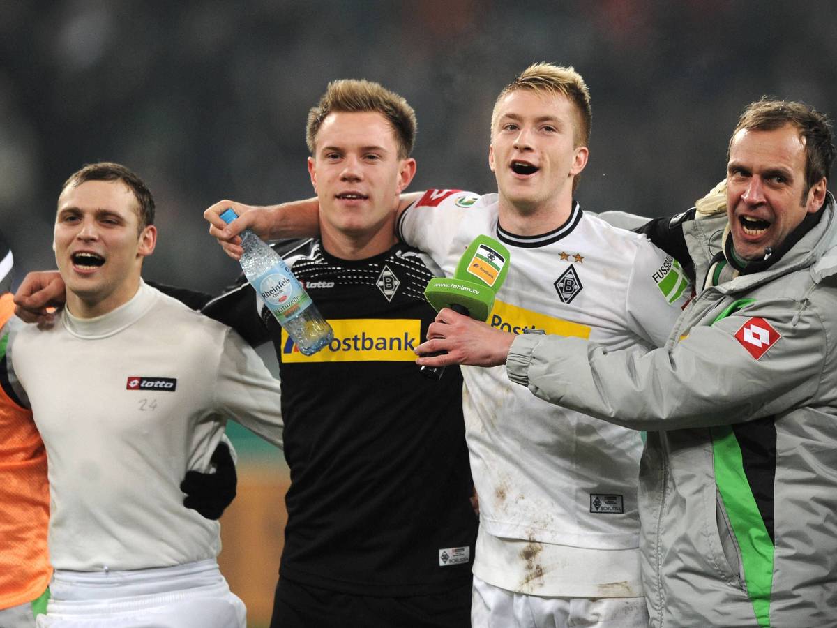 Tony Jantschke, Marc-André ter Stegen, Marco Reus und Stadionsprecher Thorsten Knippertz jubeln vor der Kurve Arm in Arm.
