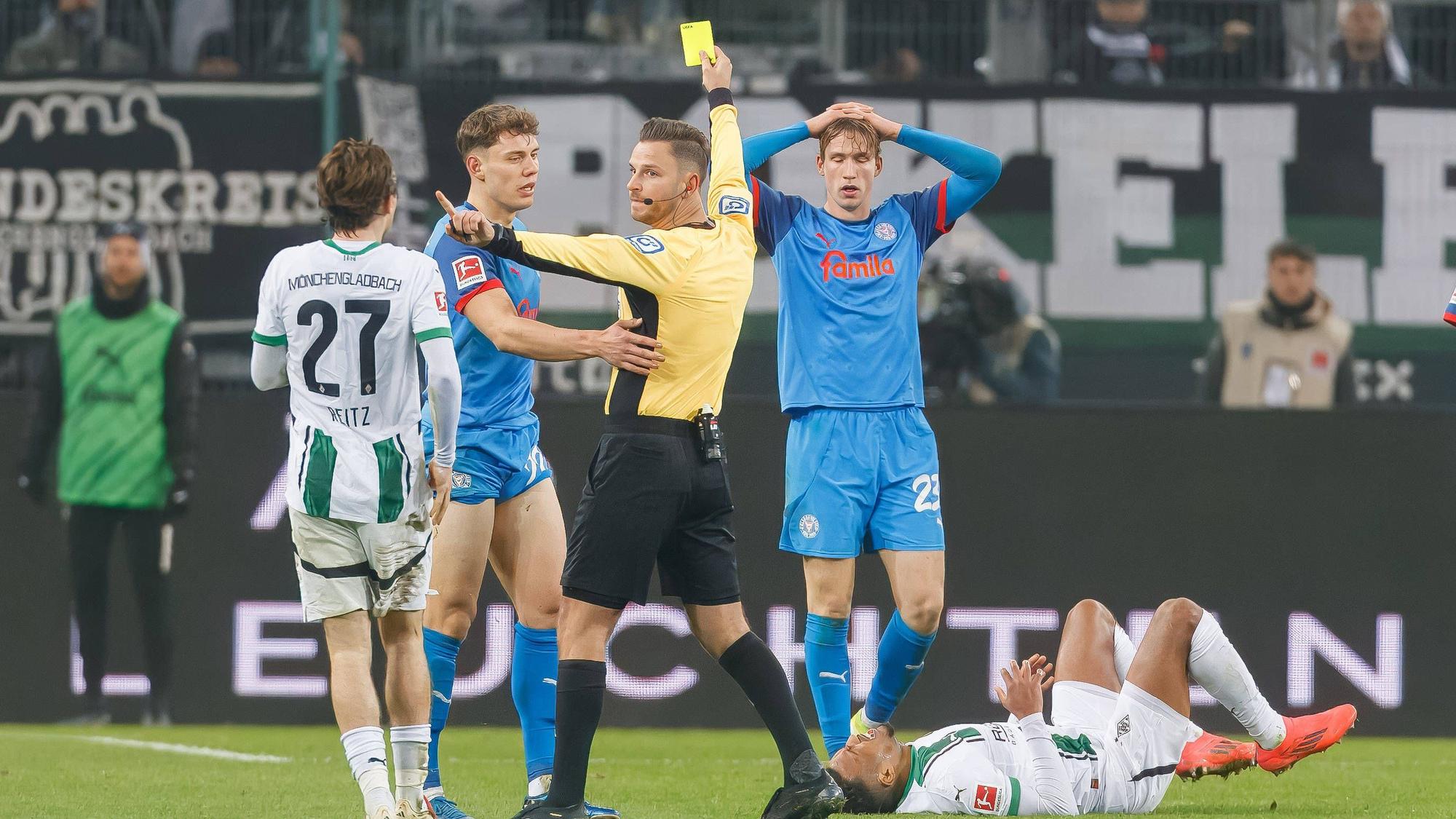 Daniel Schlager zeigt einem Spieler von Holstein Kiel die Gelbe Karte.