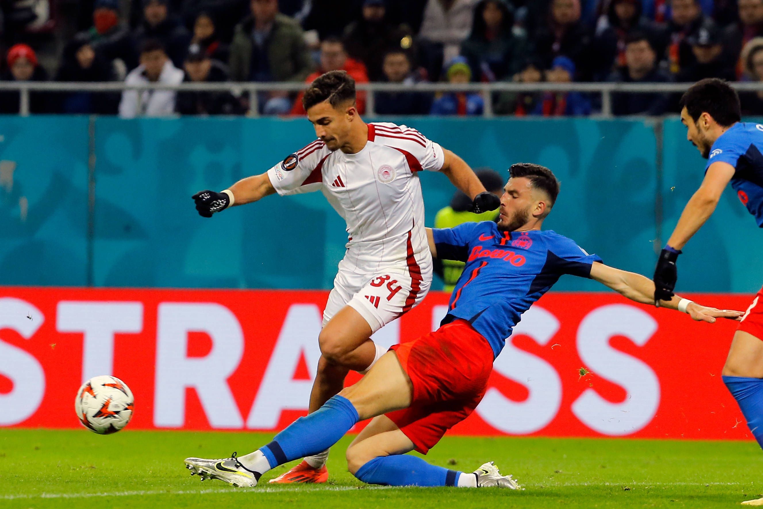 Olympiakos-Profi Charalampos Kostoulas wird im Europa-League-Spiel bei FCSB Bukarest von seinem Gegenspieler abgegrätscht.