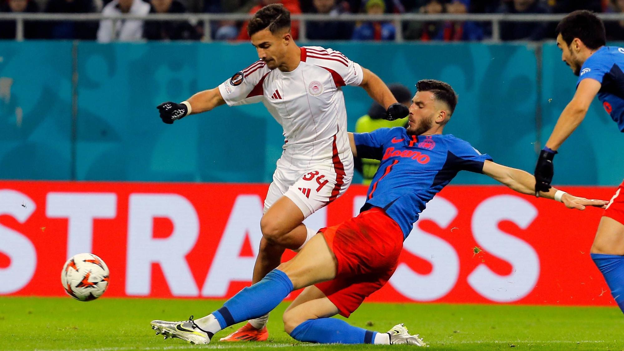 Olympiakos-Profi Charalampos Kostoulas wird im Europa-League-Spiel bei FCSB Bukarest von seinem Gegenspieler abgegrätscht.