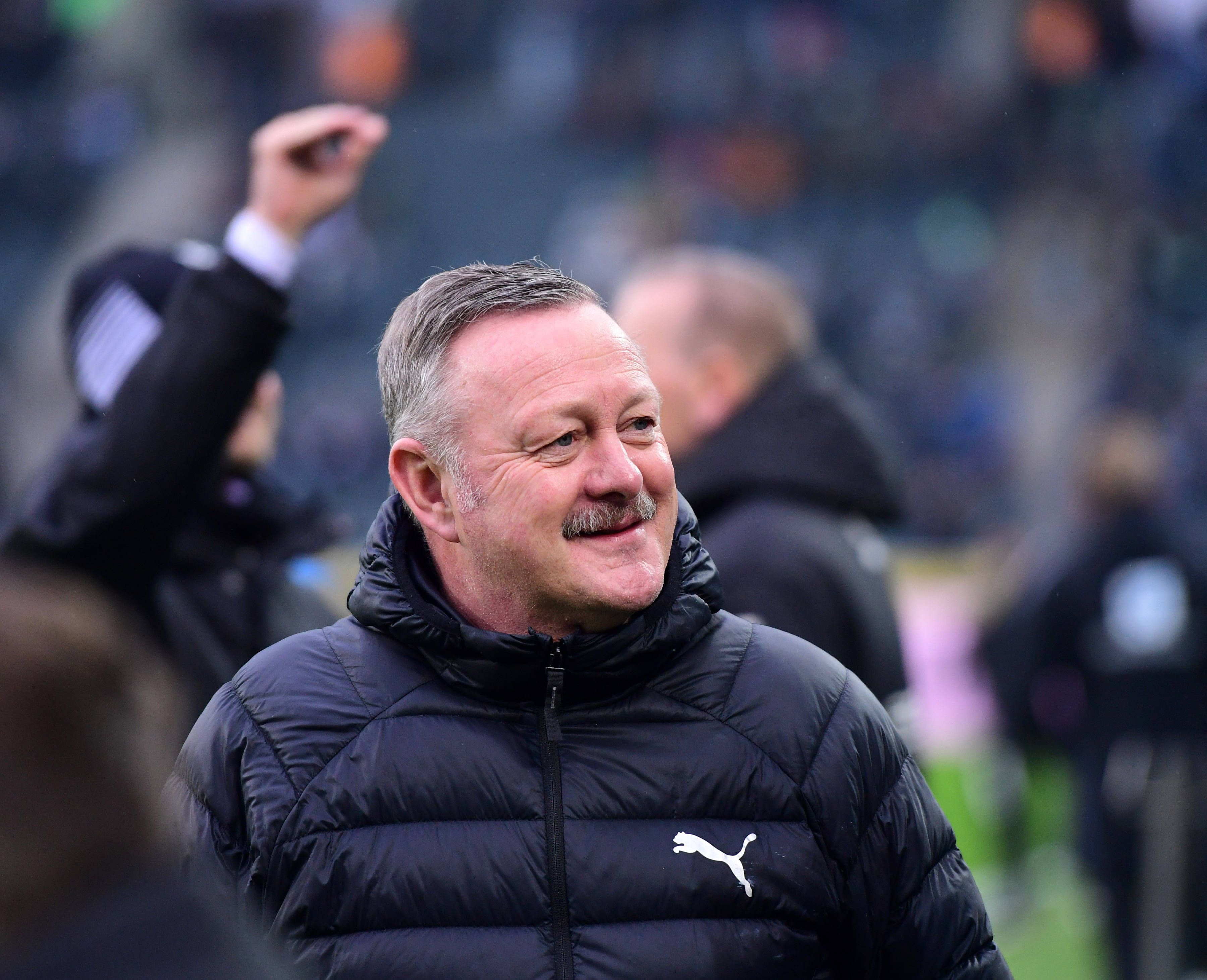 Roland Virkus grinst vor einem Spiel in der Bundesliga.