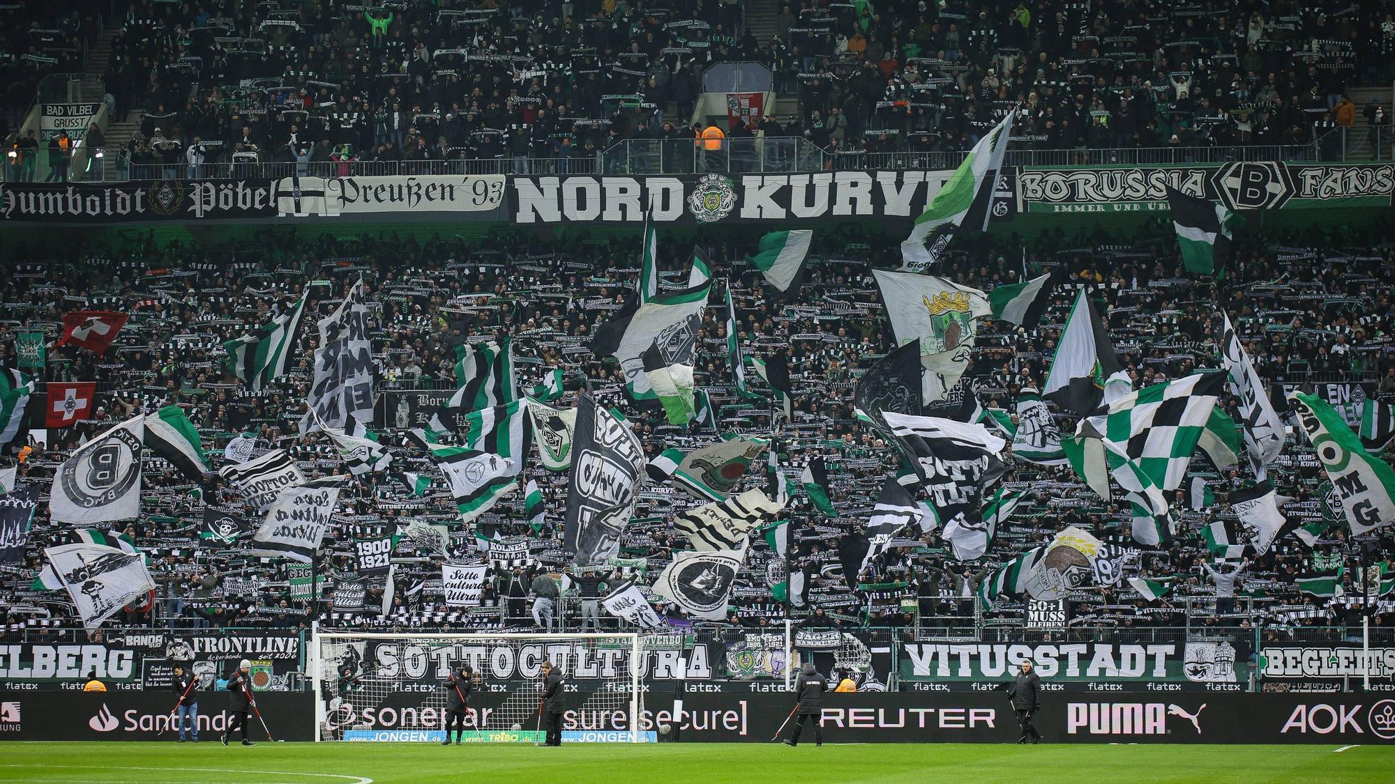 Die Fans von Borussia Mönchengladbach schwenken in der Nordkurve beim Bundesliga-Spiel gegen Holstein Kiel ihre Fahnen.