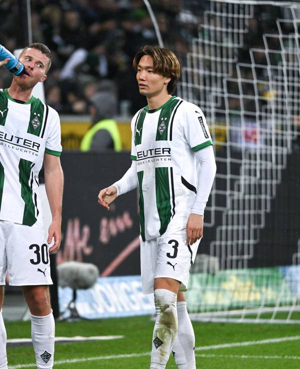 Die Gladbach-Profis Nico Elvedi und Ko Itakura stehen beim Spiel gegen Borussia Dortmund nebeneinander, Elvedi trinkt aus einer Wasserflasche.