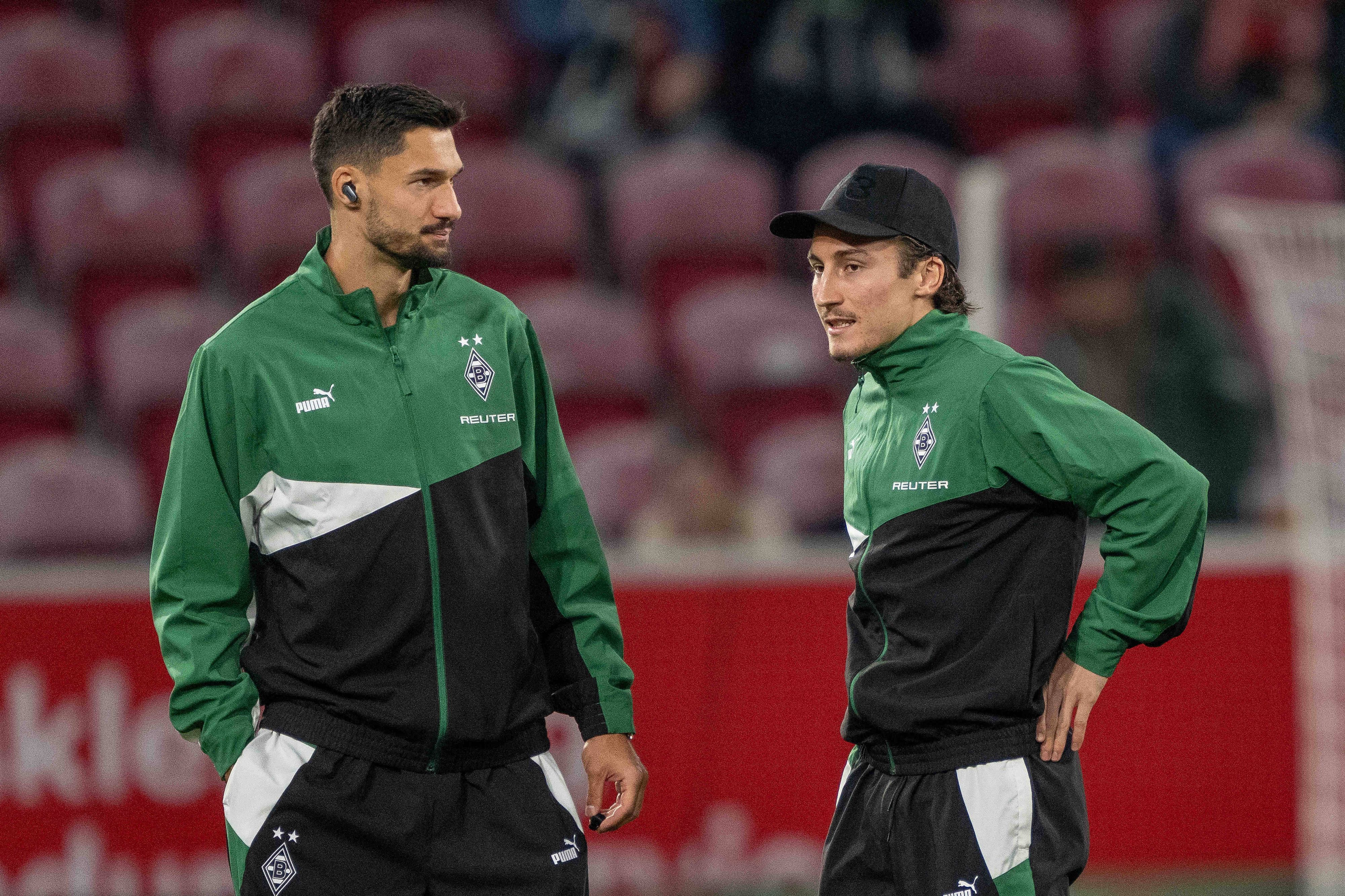Die Gladbach-Profis Tim Kleindienst und Rocco Reitz stehen vor dem Bundesliga-Spiel beim 1. FSV Mainz im Stadion und unterhalten sich.