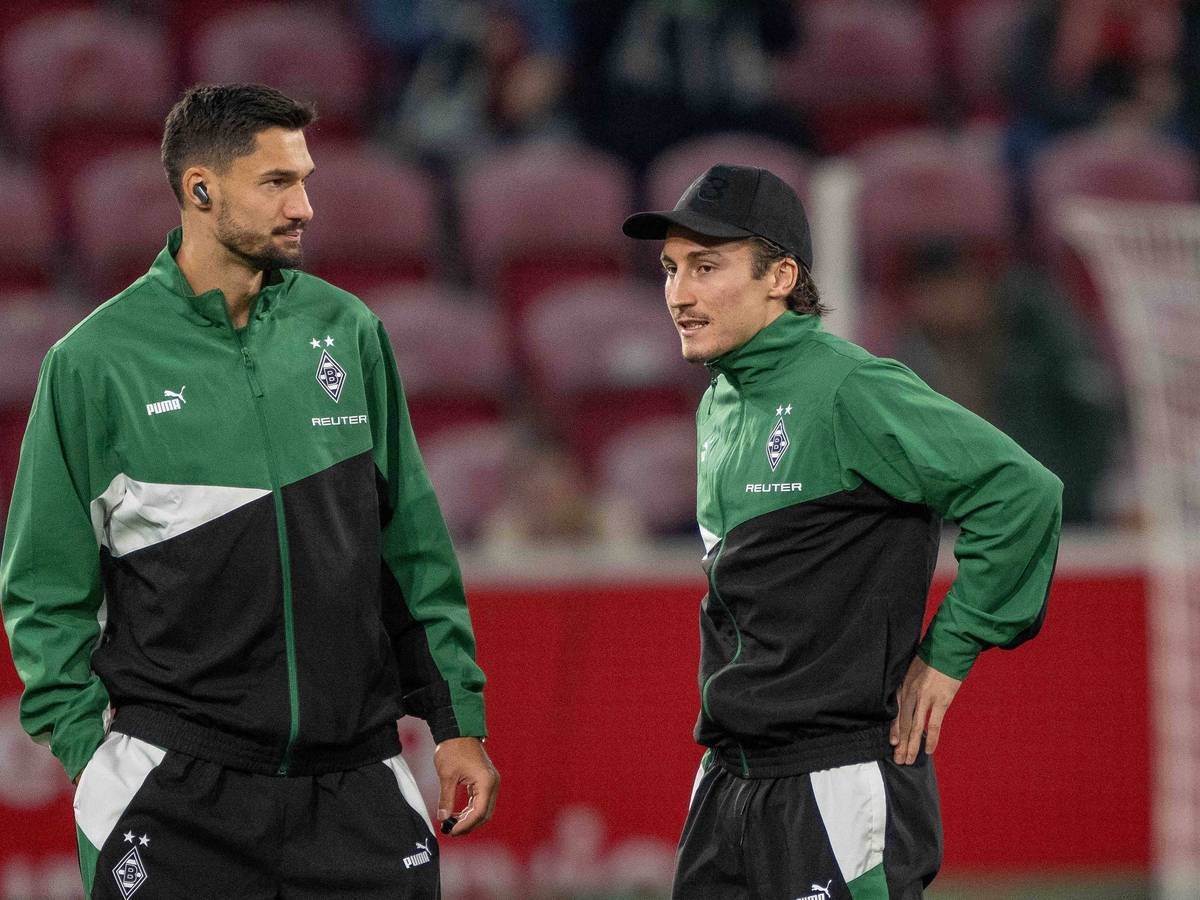 Die Gladbach-Profis Tim Kleindienst und Rocco Reitz stehen vor dem Bundesliga-Spiel beim 1. FSV Mainz im Stadion und unterhalten sich.