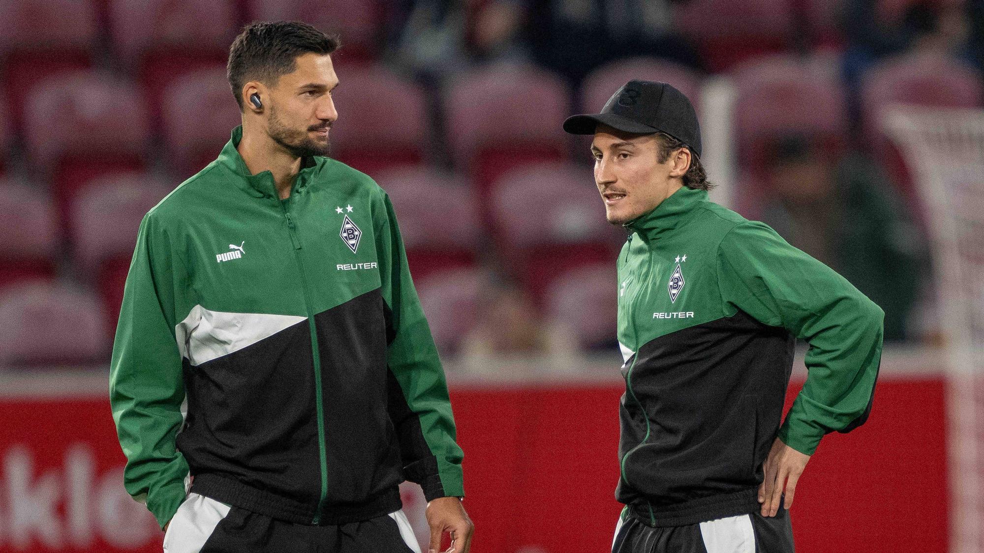 Die Gladbach-Profis Tim Kleindienst und Rocco Reitz stehen vor dem Bundesliga-Spiel beim 1. FSV Mainz im Stadion und unterhalten sich.