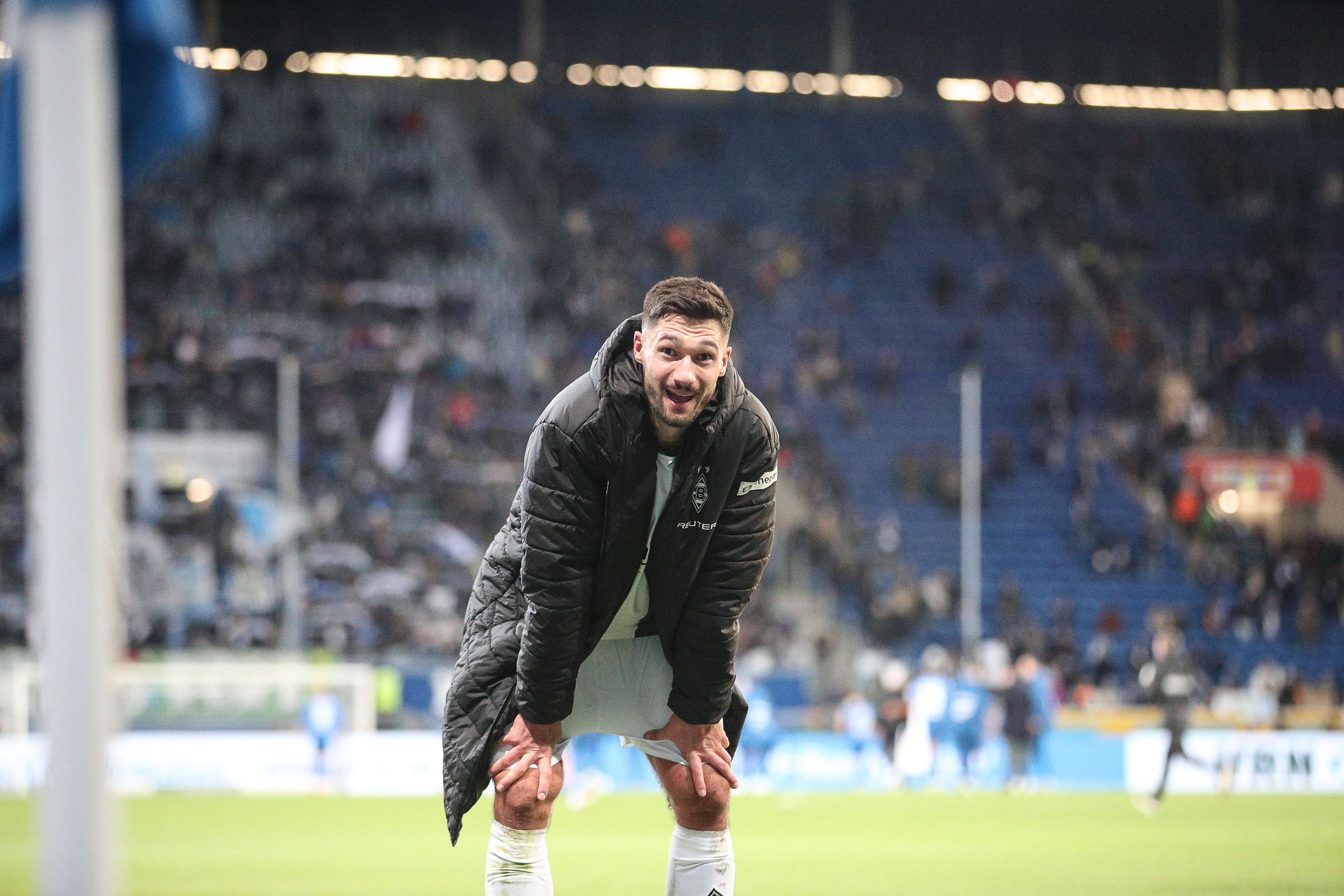 Borussia Mönchengladbachs Stürmer Tim Kleindienst steht nach dem Spiel bei der TSG Hoffenheim gebückt auf dem Platz und lächelt in die Kamera.
