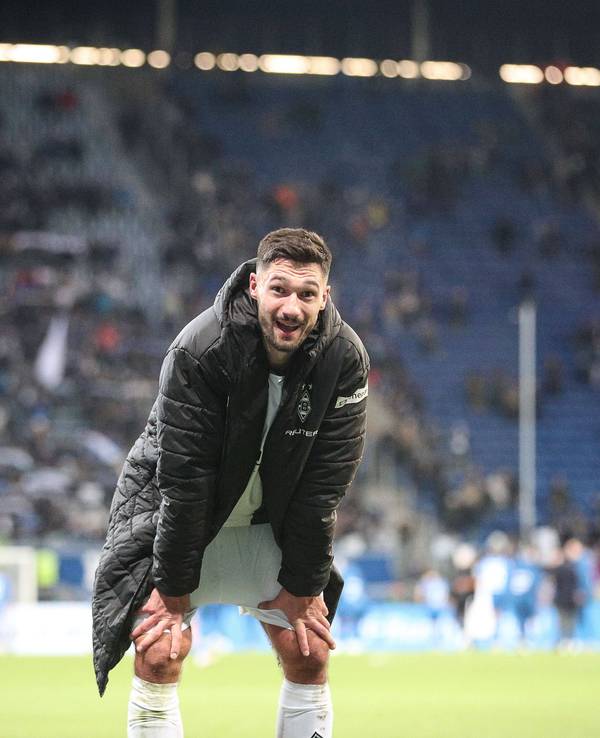 Borussia Mönchengladbachs Stürmer Tim Kleindienst steht nach dem Spiel bei der TSG Hoffenheim gebückt auf dem Platz und lächelt in die Kamera.