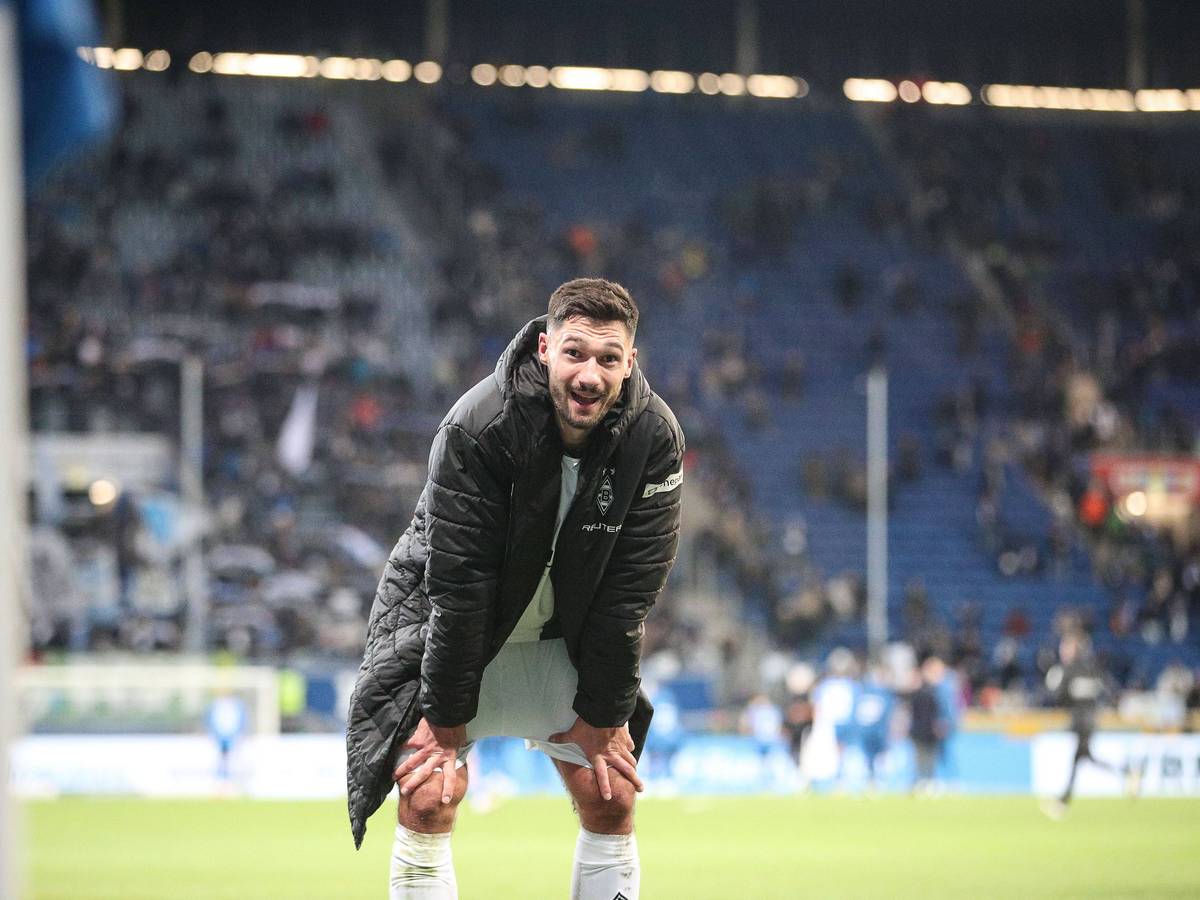 Borussia Mönchengladbachs Stürmer Tim Kleindienst steht nach dem Spiel bei der TSG Hoffenheim gebückt auf dem Platz und lächelt in die Kamera.