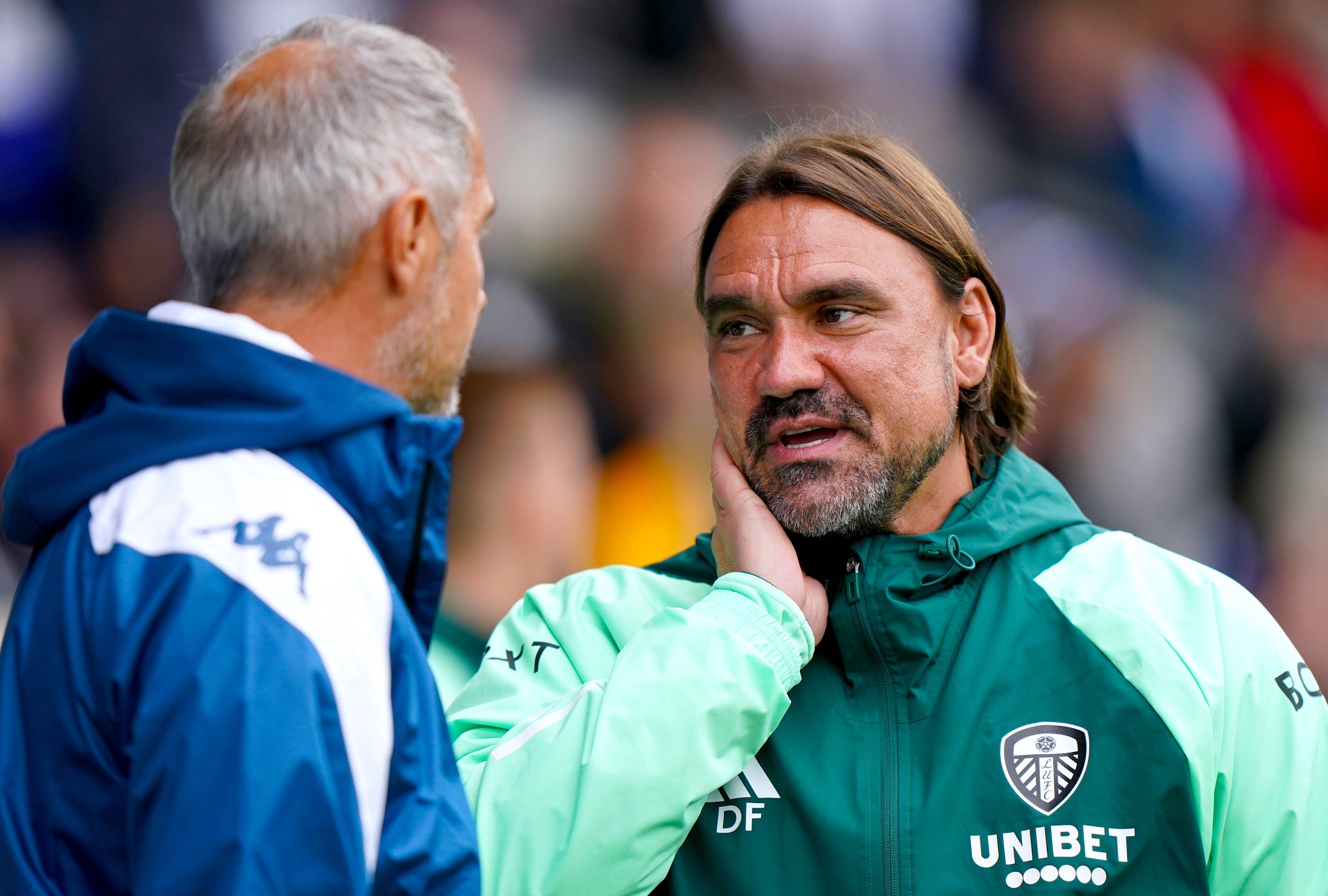Daniel Farke unterhält sich in Regenjacke mit Adi Hütter am Seitenrand.
