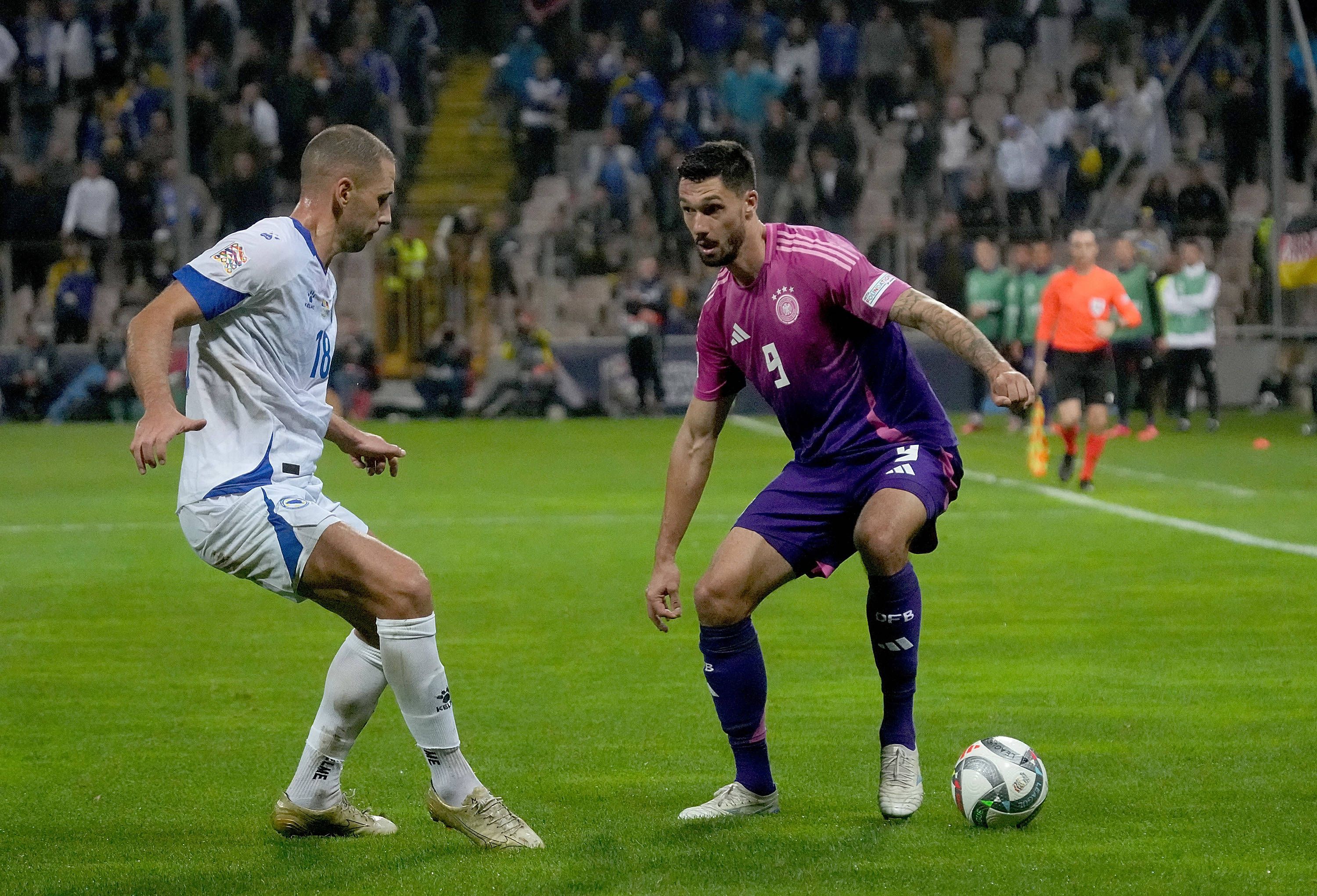 Deutschlands Nationalspieler Tim Kleindienst führt den Ball im Nations-League-Spiel in Bosnien-Herzegowina. Gegenspieler Nikola Katic versucht, ihn zu stellen.