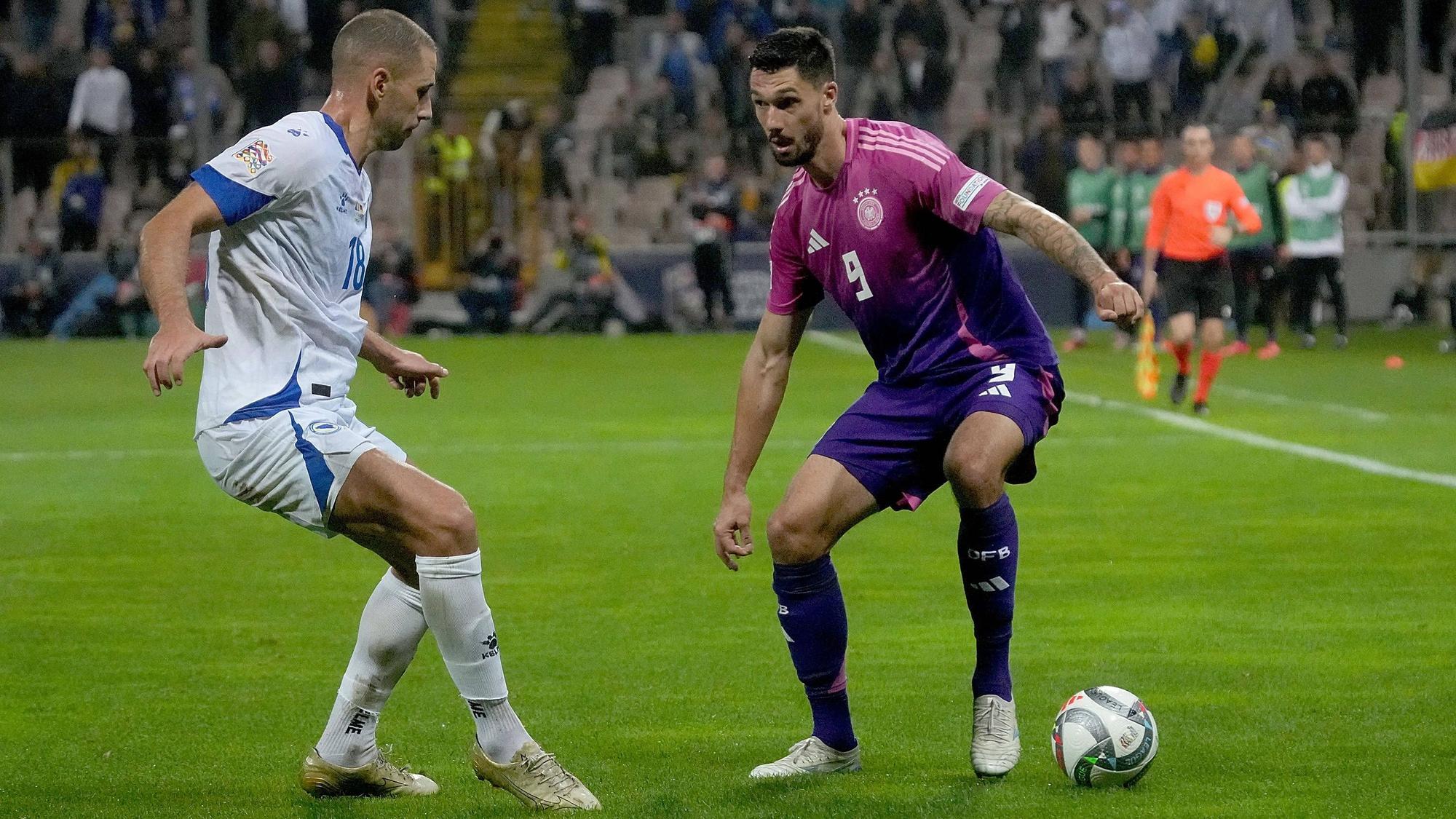 Deutschlands Nationalspieler Tim Kleindienst führt den Ball im Nations-League-Spiel in Bosnien-Herzegowina. Gegenspieler Nikola Katic versucht, ihn zu stellen.