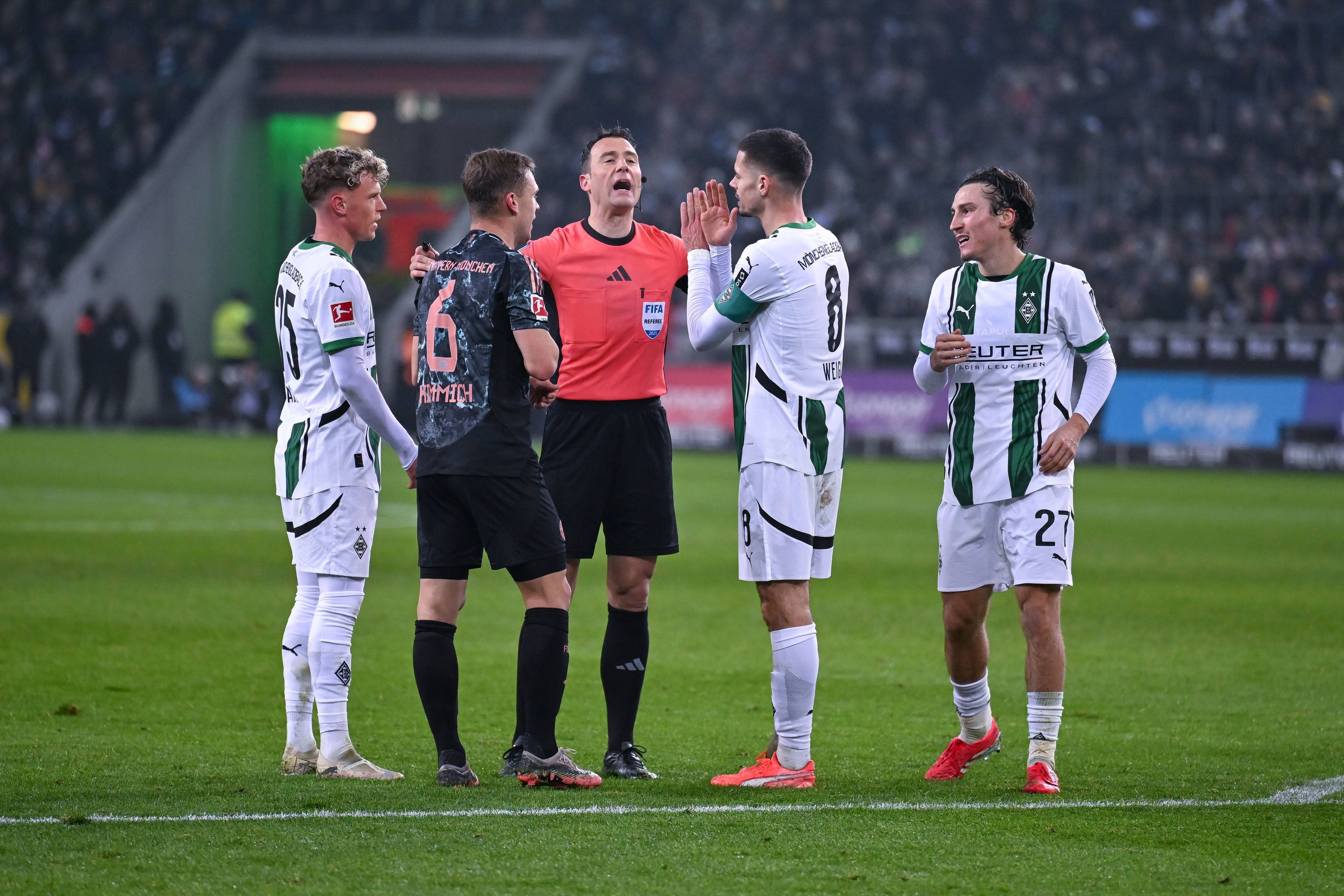 Felix Zwayer erklärt drei Gladbachern und einem Bayern-Spieler eine Entscheidung.
