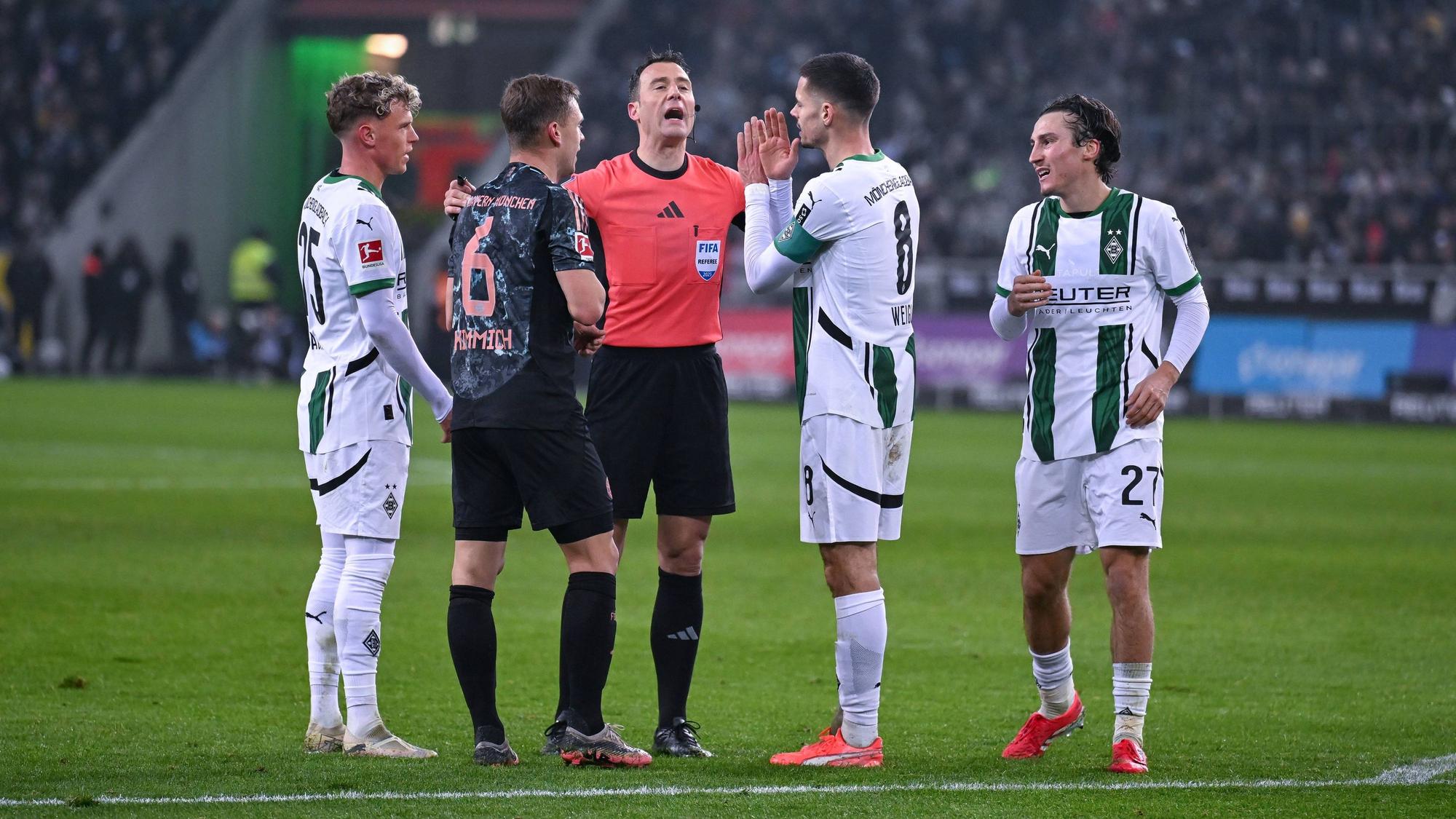Felix Zwayer erklärt drei Gladbachern und einem Bayern-Spieler eine Entscheidung.