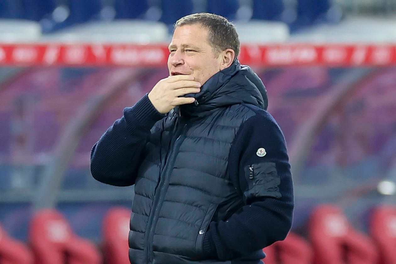 Bayern Münchens Sport-Vorstand Max Eberl steht beim Testspiel in Salzburg lächelnd im Stadion und legt die Hand vor den Mund.